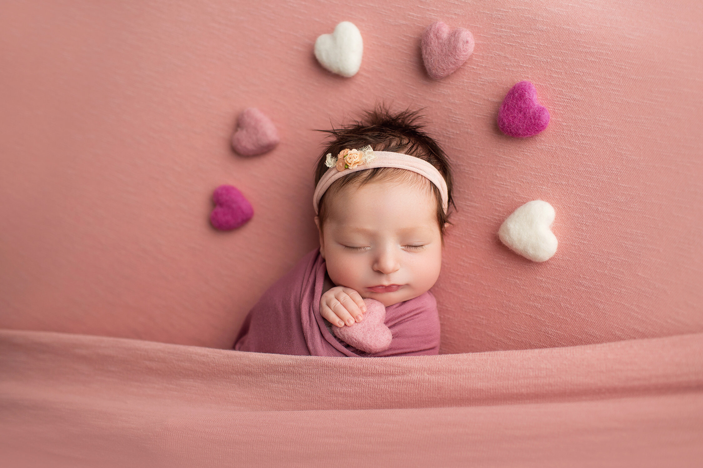 sweet newborn in a blanket with hearts circling her head