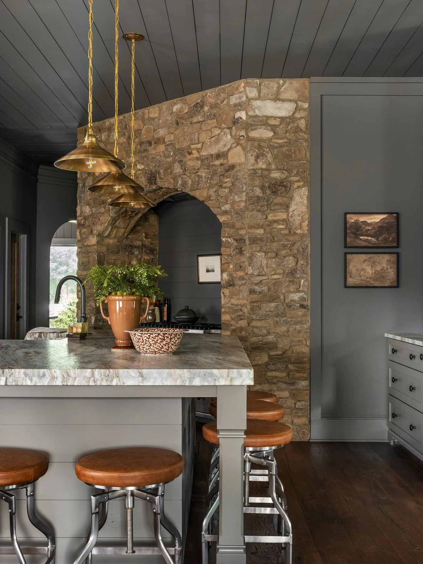 Who else loves this kitchen vibe? 🩶

Natural stone, deep wood tones, and burnished brass create a kitchen that feels both timeless and full of character. 

The arched stone surround makes a bold architectural statement, while the leather-topped stoo