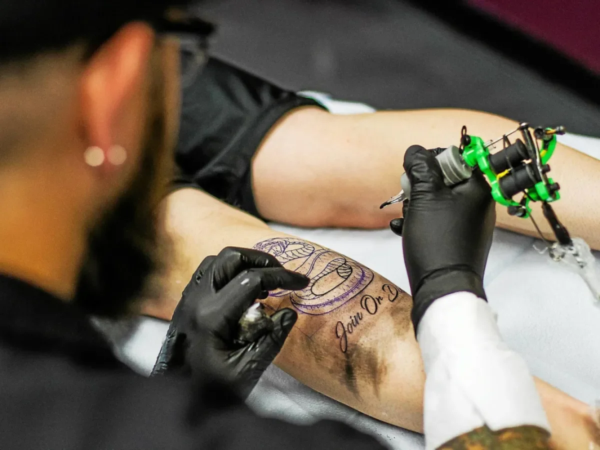 Tattooing in progress, with a snake design and Join or Die lettering