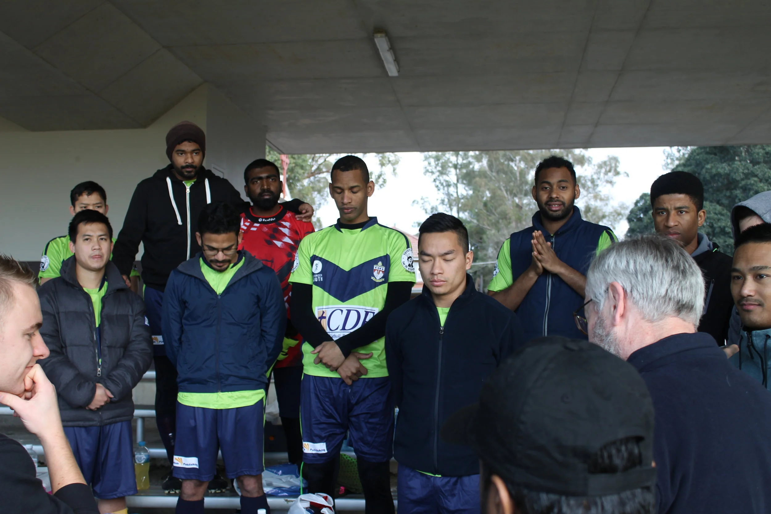 Rector, Fr Denis Stanley, prays with the Corpus Christi College soccer team.