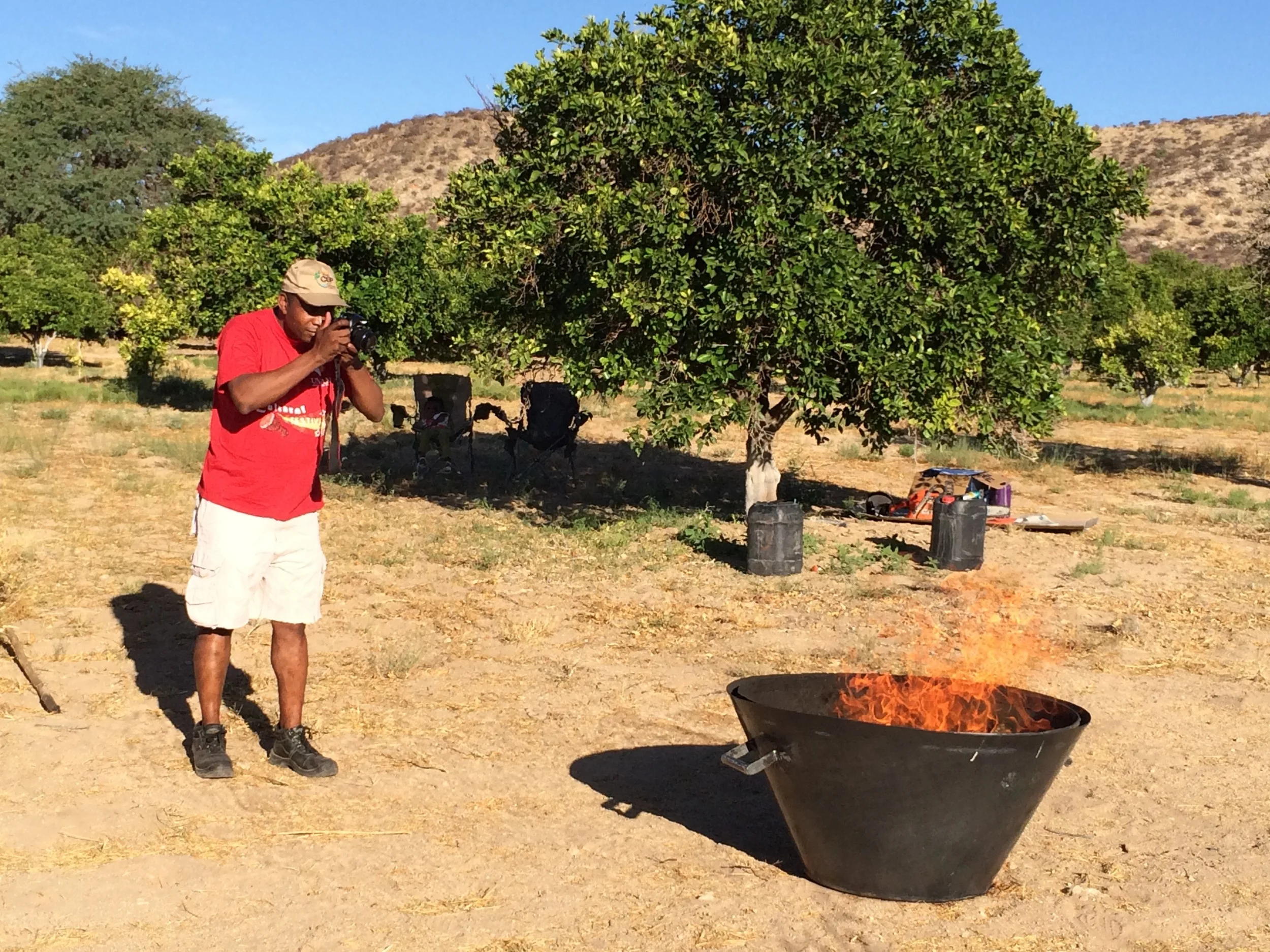 Dr Simon Angombe photographing the Kon Tiki kiln making biochar with invasive bush wood. Note no smoke.