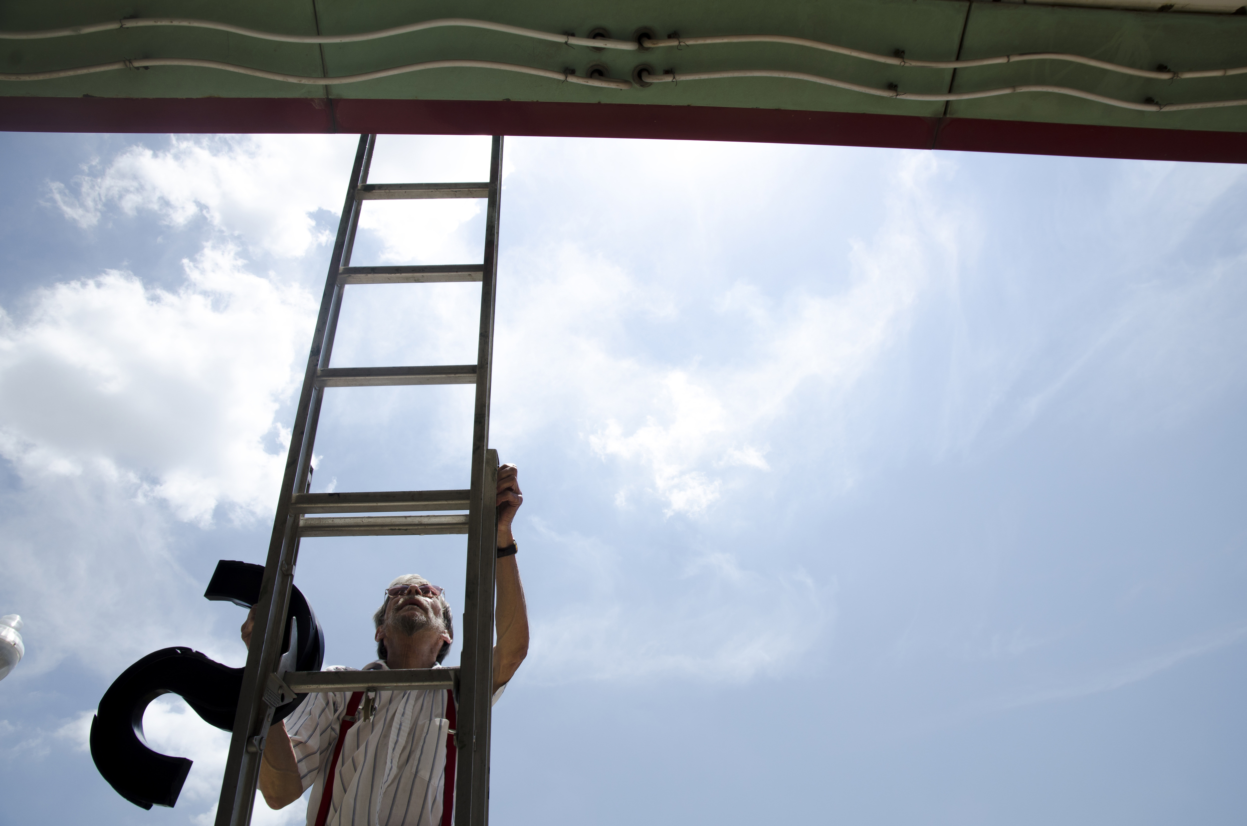   Dennis Welch, the custodian for Campus Theatre, climbs a ladder to change the marquee in Denton, Texas.  