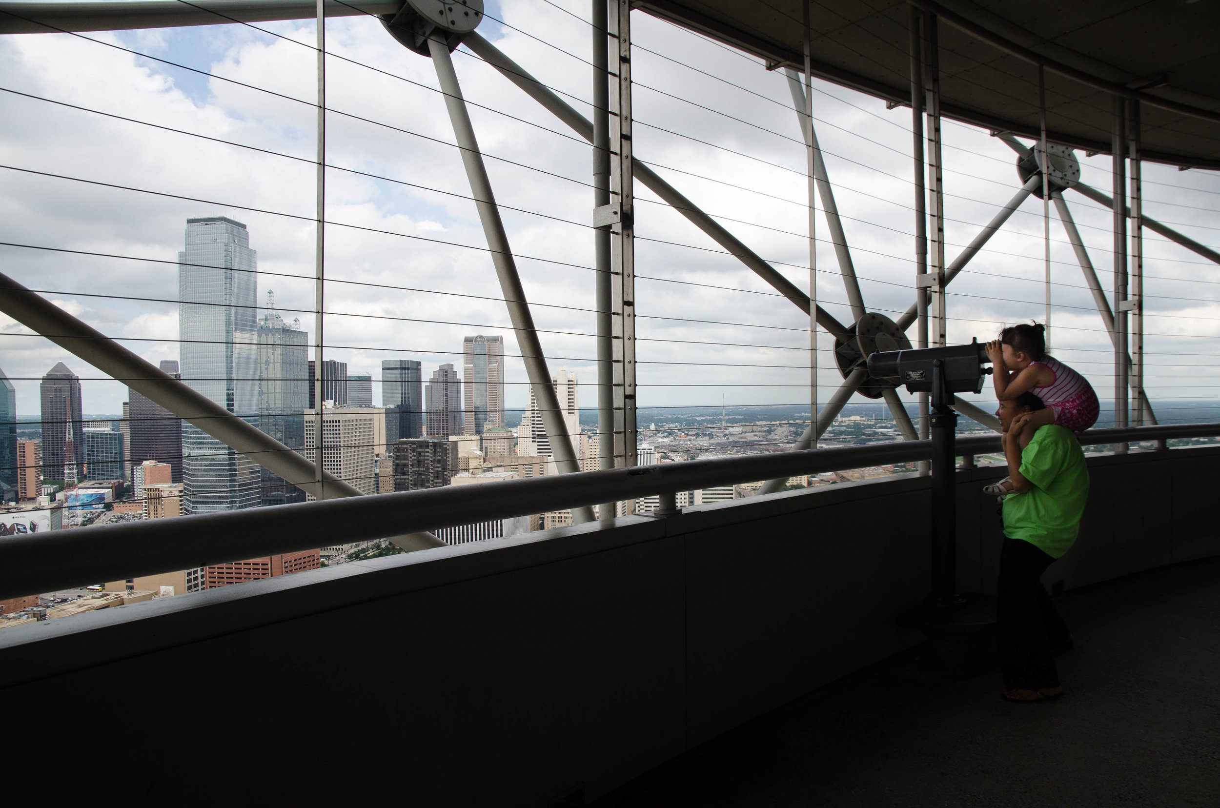 A young girl sits on her mother's shoulders to look at the view from Reunion Tower in Dallas, Texas.