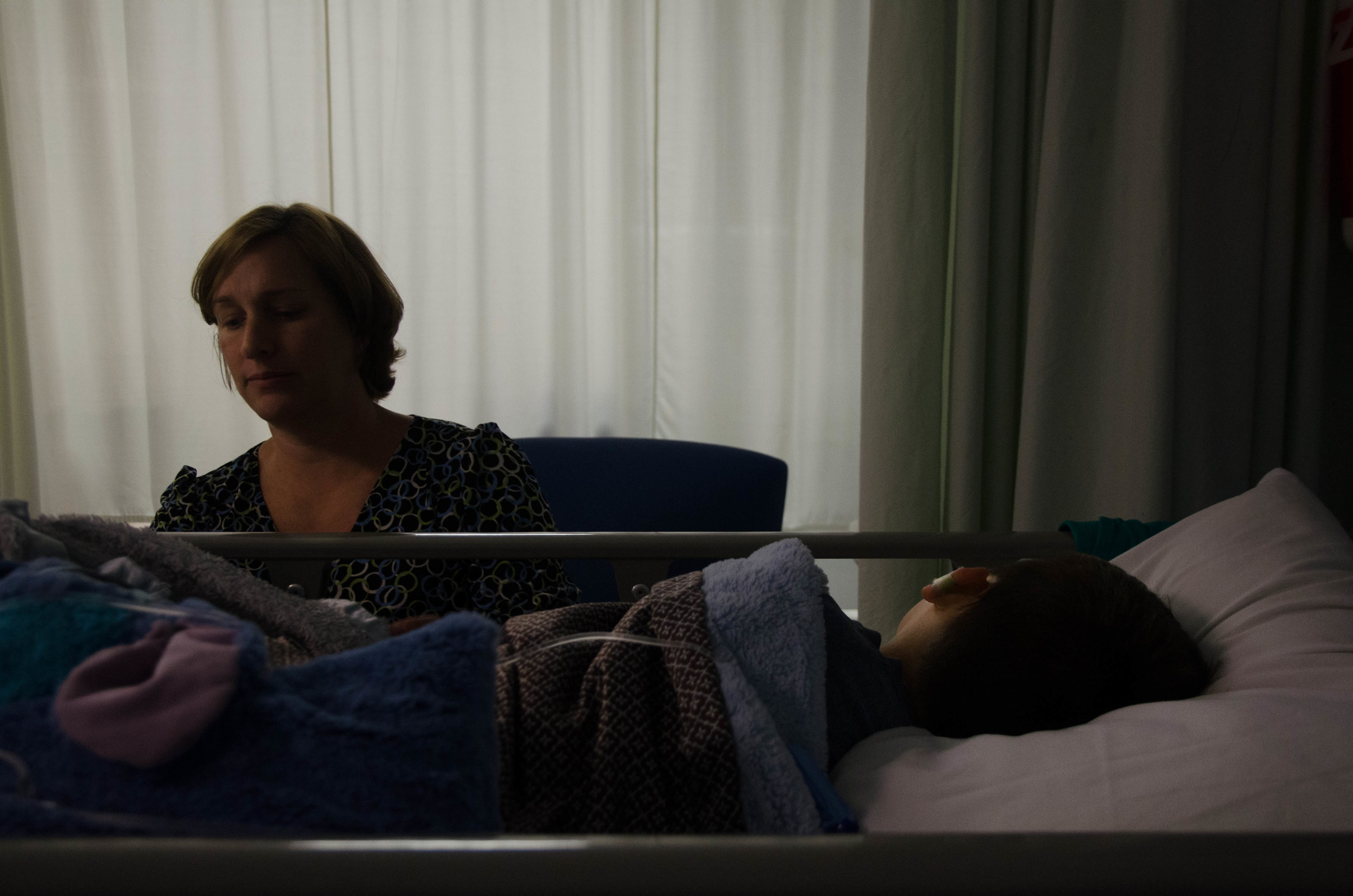 Lisa Thakker sits by the hospital bed of her son Dax Thakker as she waits for him to wake up from surgery.