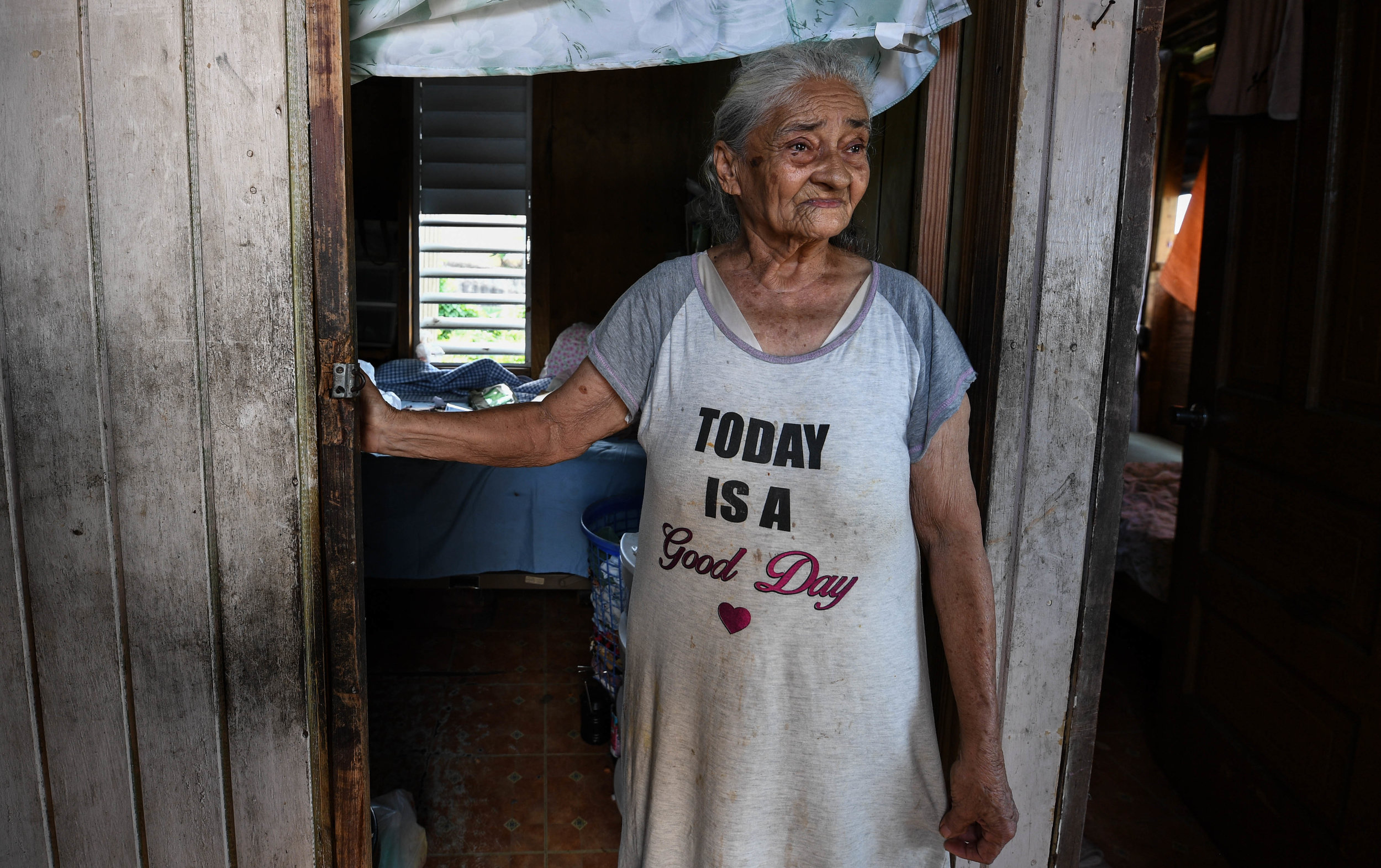 Paola Ortiz, 84, has been alone for three months, wearing the single item of clothing she has left, a T-shirt that says, "Today is a good day." In the mountain village Moca with no car, she has not yet received aid. "I've always been poor," said Ort