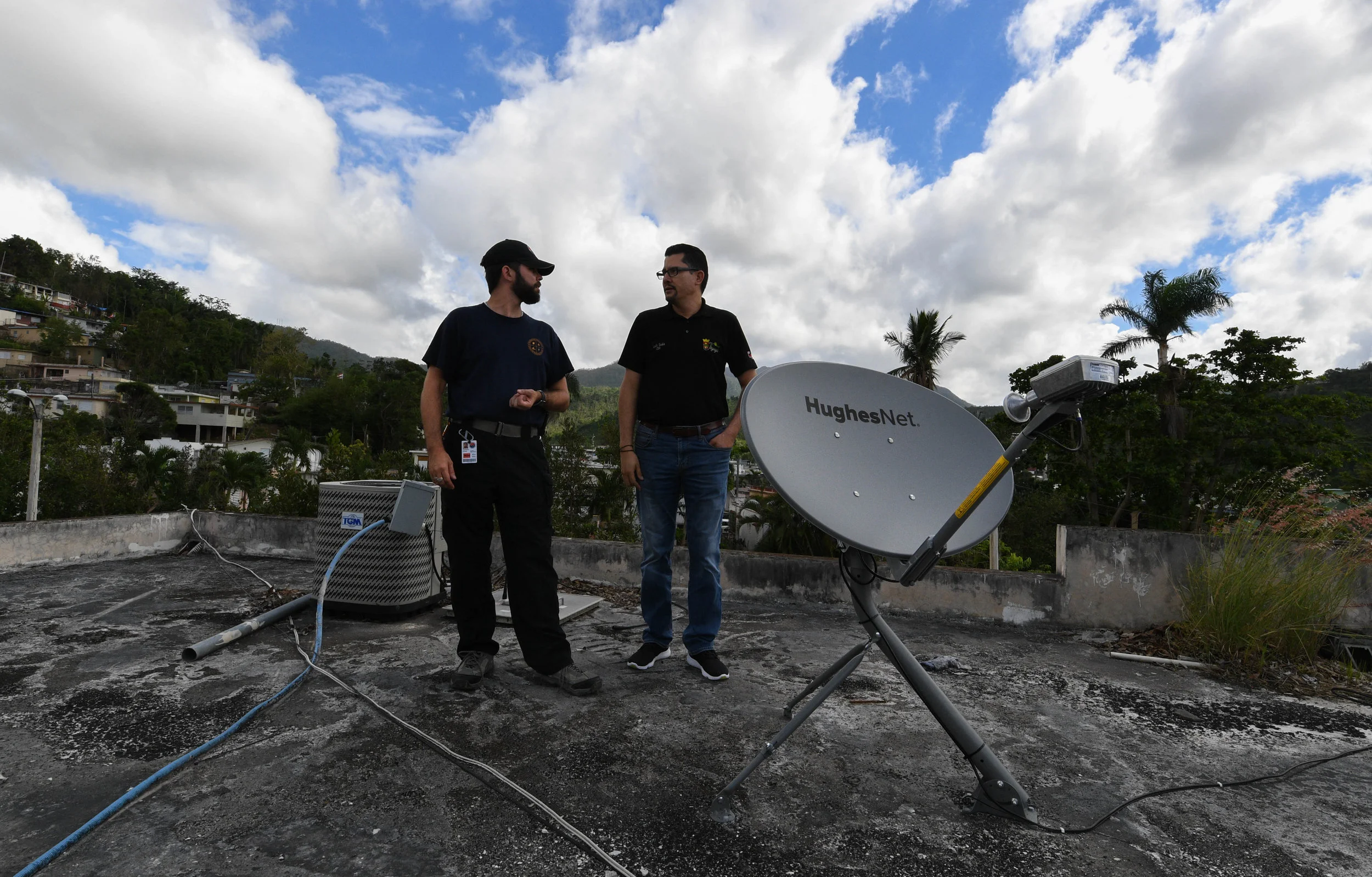 EXPAND Darrick Kouns, a volunteer with Dallas-based nonprofit Information Technology Disaster Resource Center, discusses with Luis Seda, the network administrator for the mayor's office in the mountain village Jayuya, how they can supply communications for the local shelter. ITDRC deploys volunteers from all over the world to provide communities affected by disasters with resources to recover their IT infrastructure. Providing internet access and phones helps families reconnect when separated and aids businesses in reopening.