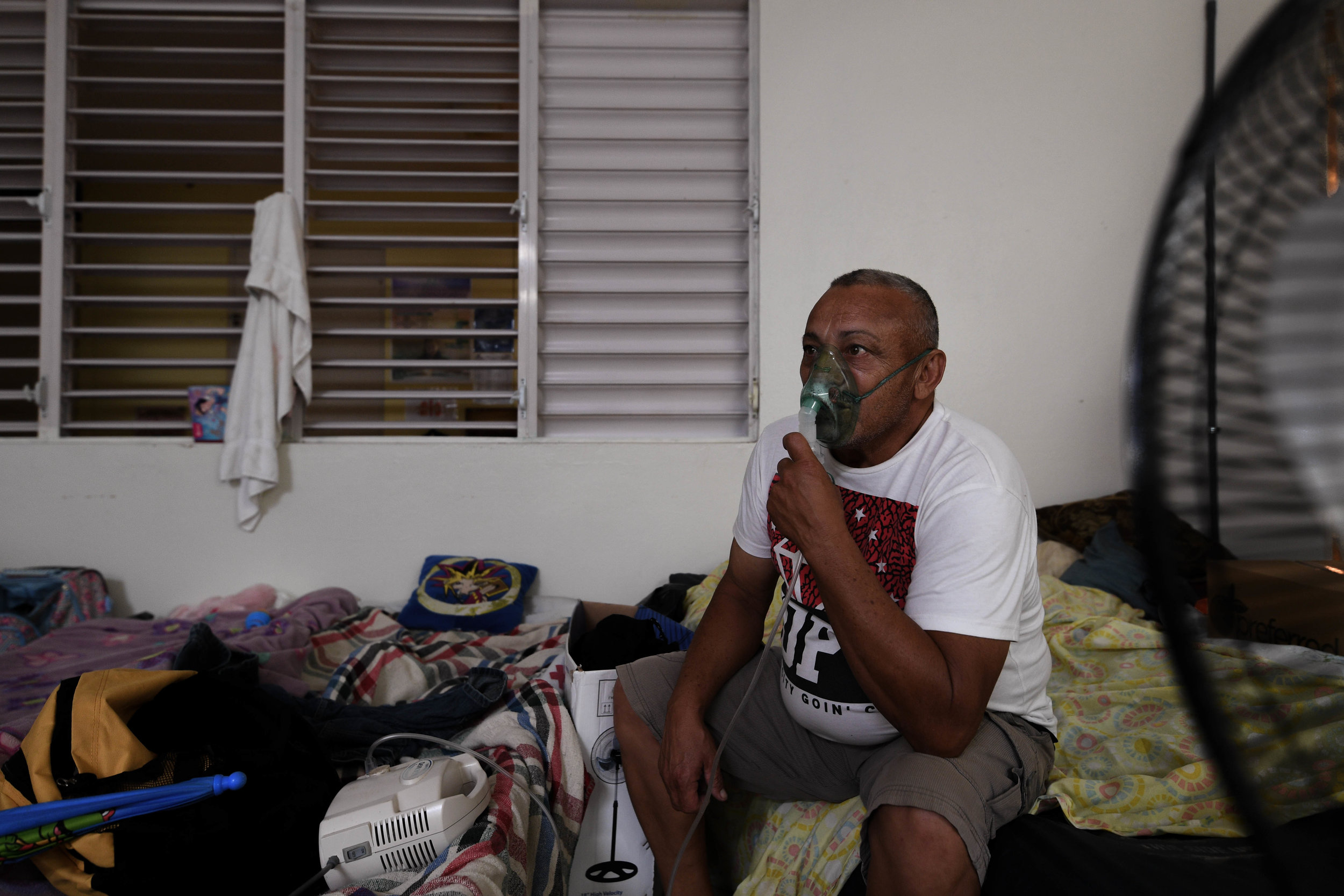  Alfredo Matos Rivera, 58, sits on the edge of his cot next to other displaced families while focusing on his breathing treatement. Matos has been in the shelter outside of Dominguito for more than 72 days. Hospitals in his area remain without power,