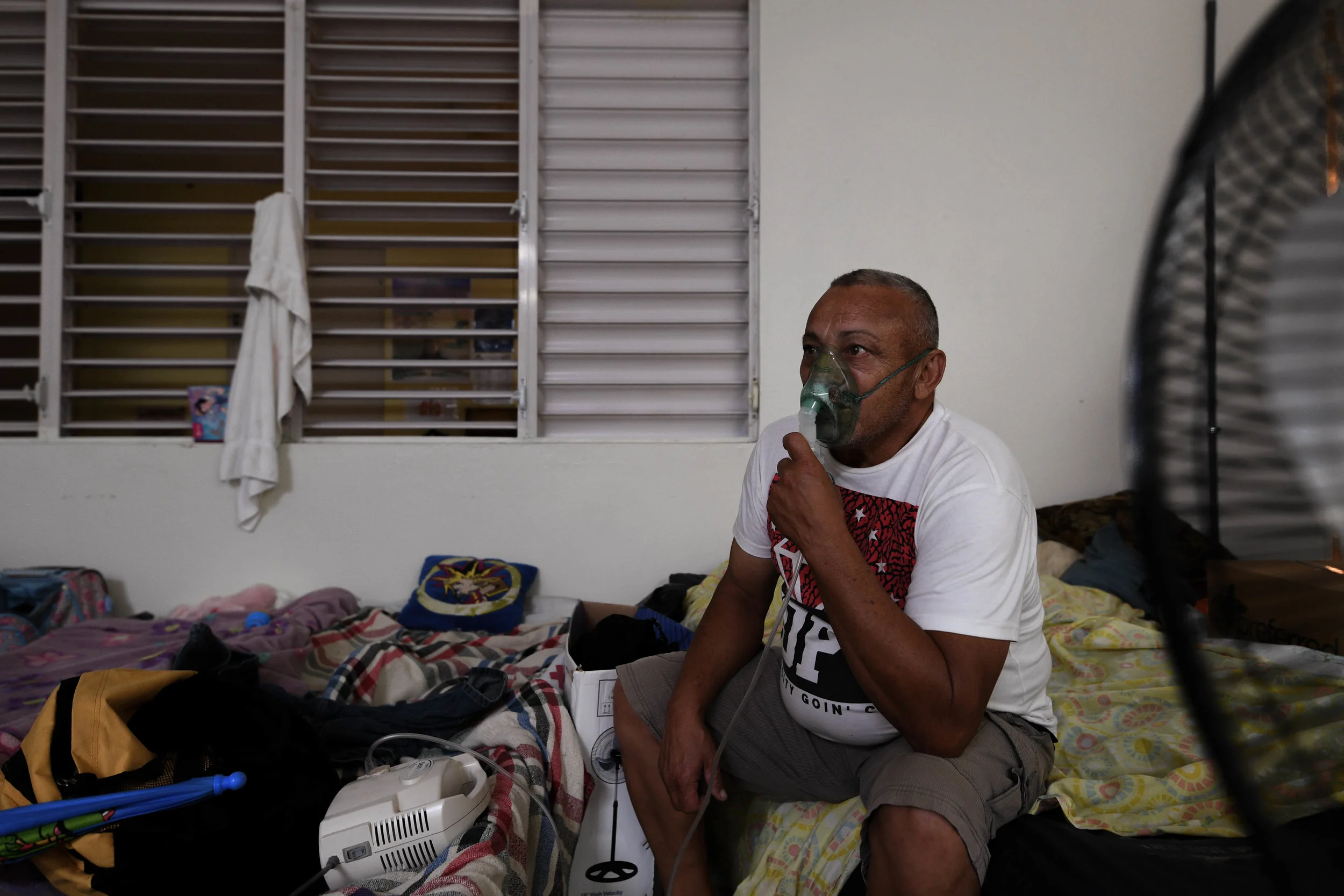Alfredo Matos Rivera, 58, sits on the edge of his cot next to other displaced families while focusing on his breathing treatement. Matos has been in the shelter outside of Dominguito for more than 72 days. Hospitals in his area remain without power, and with the loss of his house, job and car, traveling to a hospital in his area is not an option.