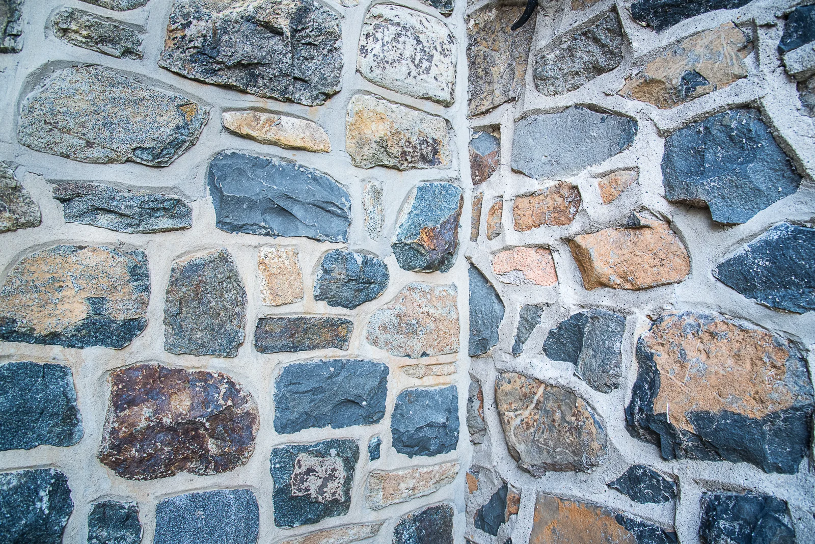 Close-up of a stone wall made of irregularly shaped stones with mortar filling the gaps.