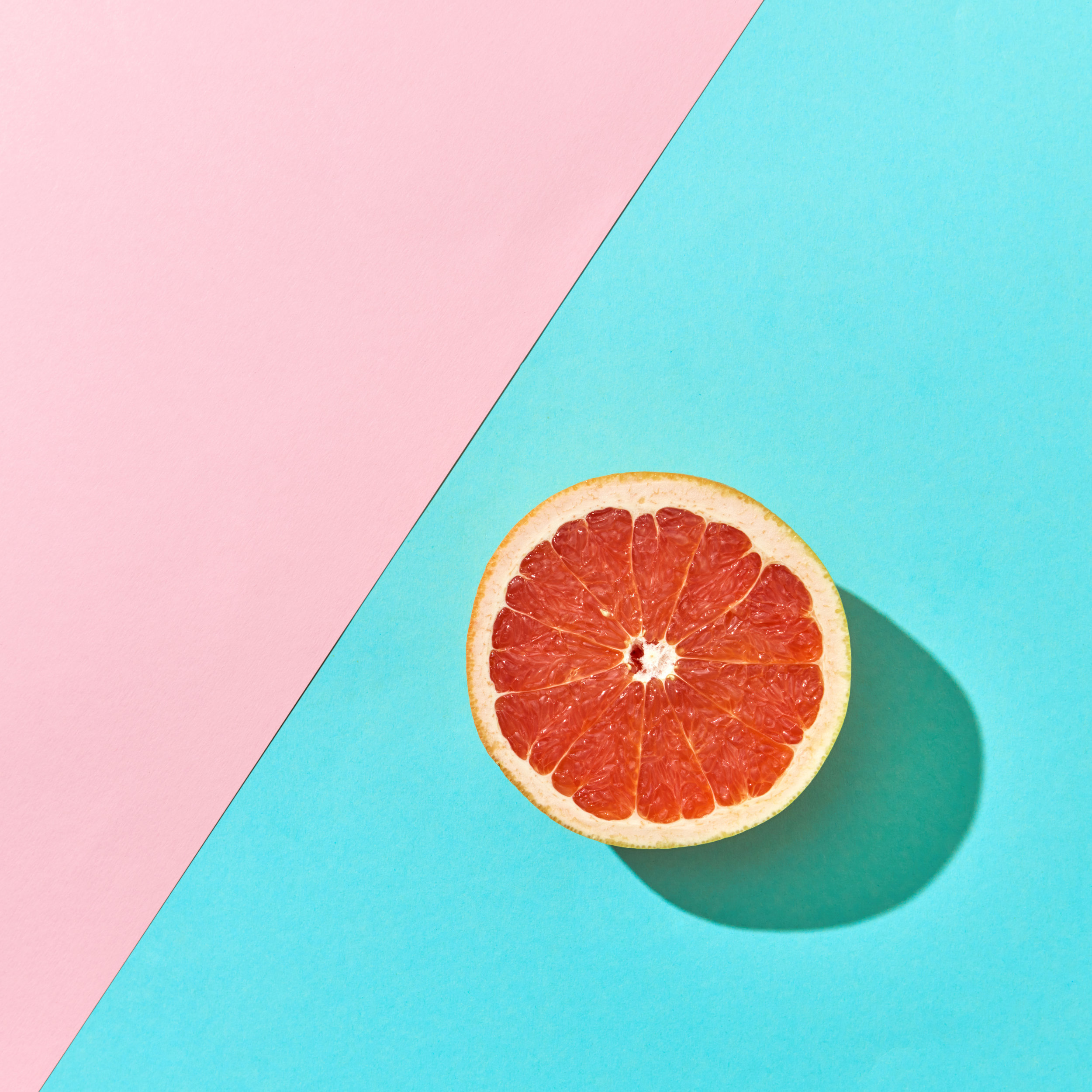 Juicy half of citrus grapefruit on a blue-pink cardboard background with copy space. Top view
