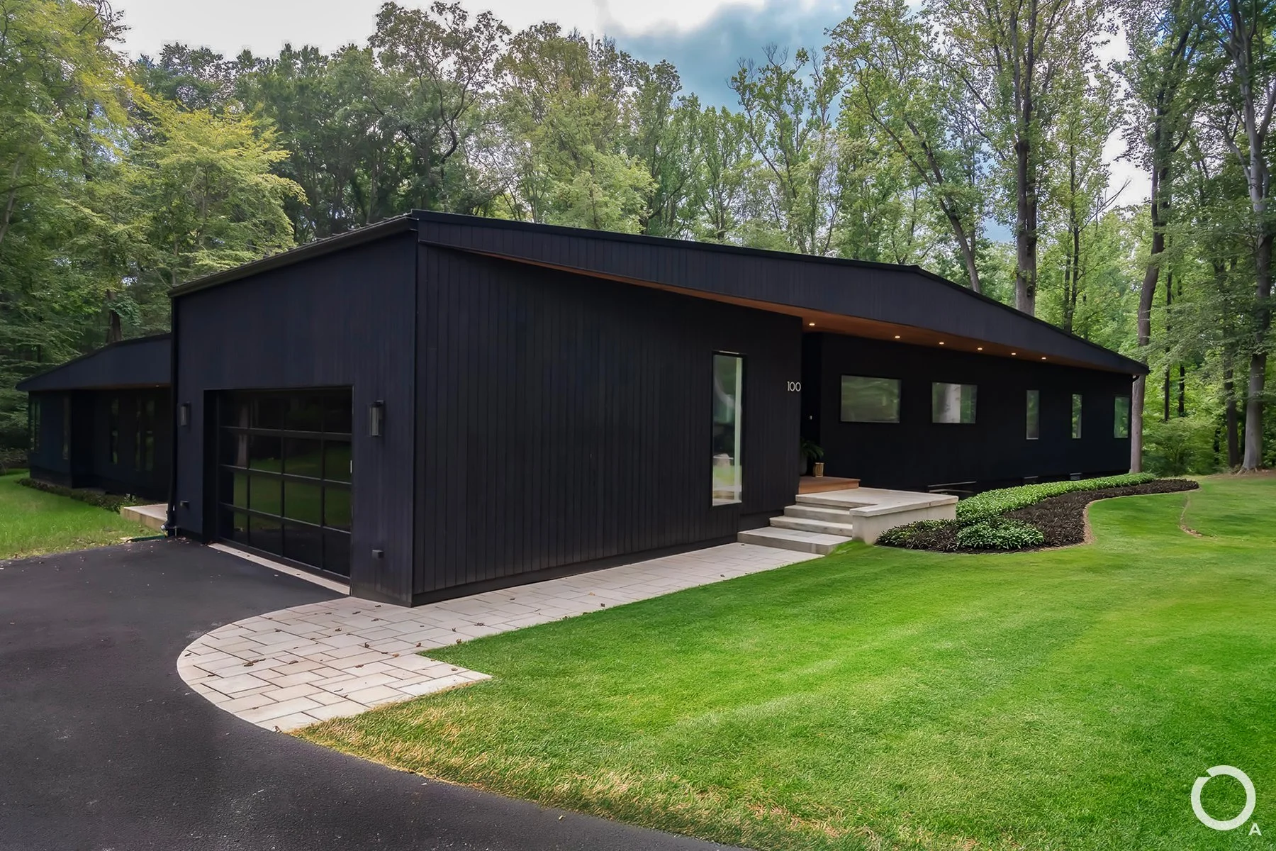 Modern home entrance with black vertical wood siding, glazed garage door, concrete entry steps, and an angular roofline in Chadds Ford, PA. Photo Credit: Linda McManus Photography
