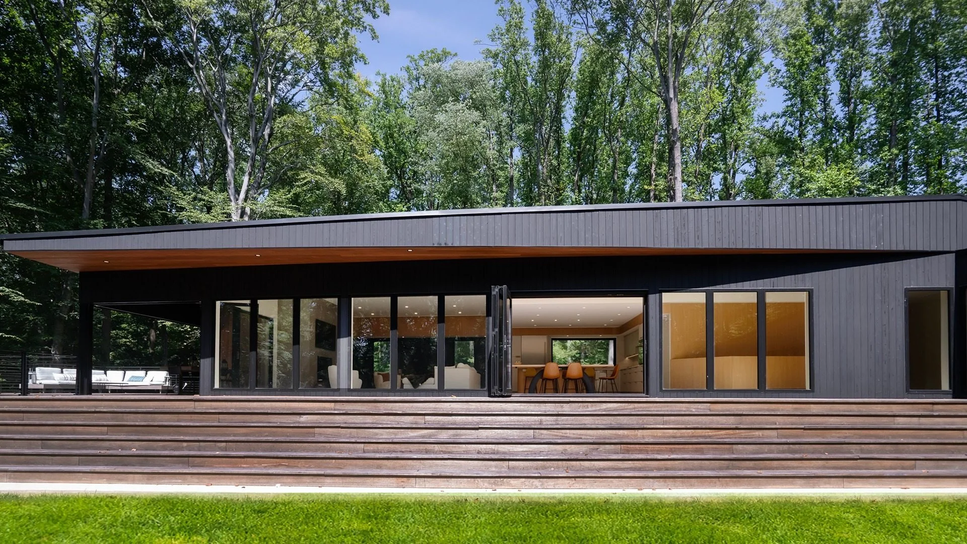 Timber Ridge House in Chadds Ford, PA, by ONY Architecture, showing the dark-clad garden elevation, expansive glass doors, and broad timber terrace.