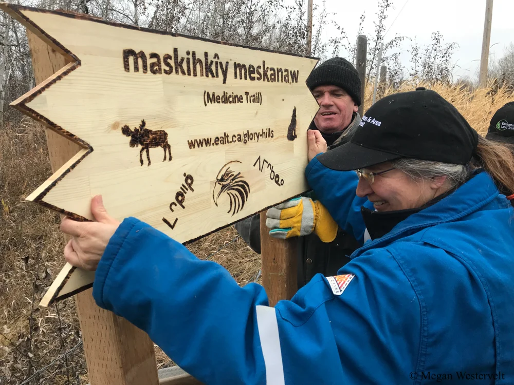 A volunteer with Cree heritage helps to install the new sign bearing the recently selected indigenous name for Glory Hills: maskihkîy meskanaw. Thanks to collaborative efforts between EALT, amiskwaciy Academy, and MacEwan University, those who visit can once again connect with the area’s ancient roots.