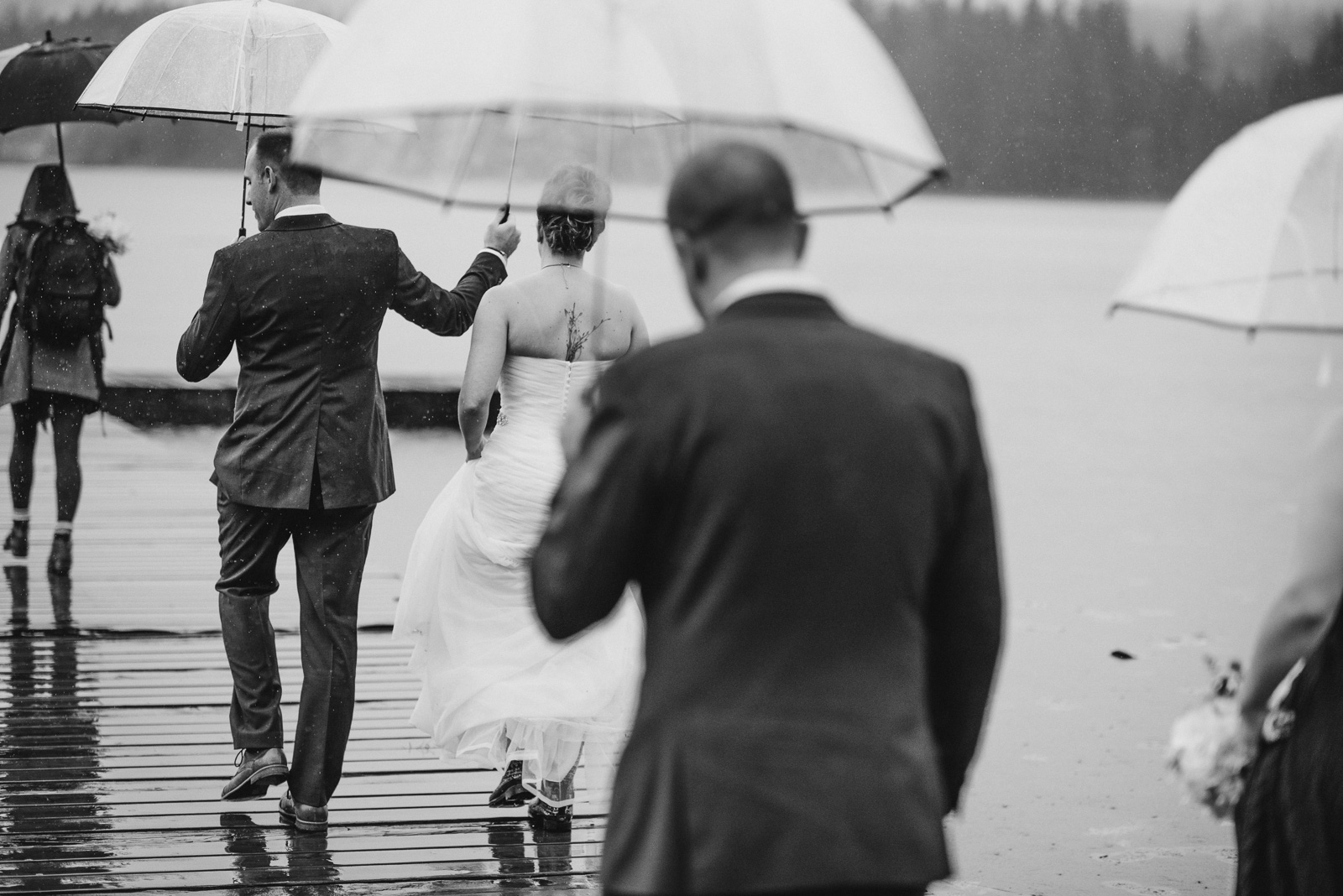 bride and groom walking out onto the dock in the rain at Whonnock Lake Centre in Maple Ridge - Victoria Wedding Photographers