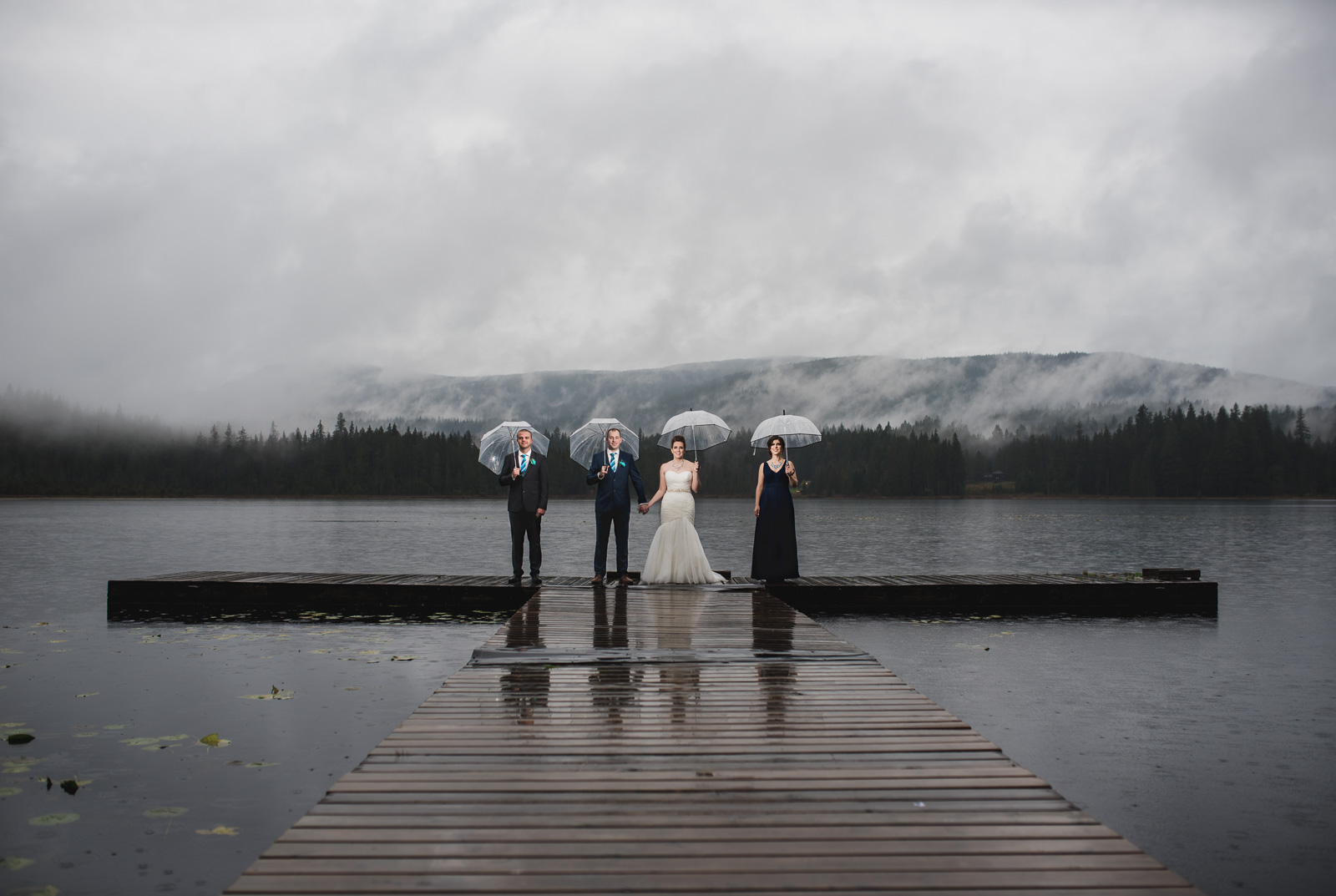 wedding party standing in the rain on the dock at at Whonnock Lake Centre in Maple Ridge - Victoria Wedding Photographers