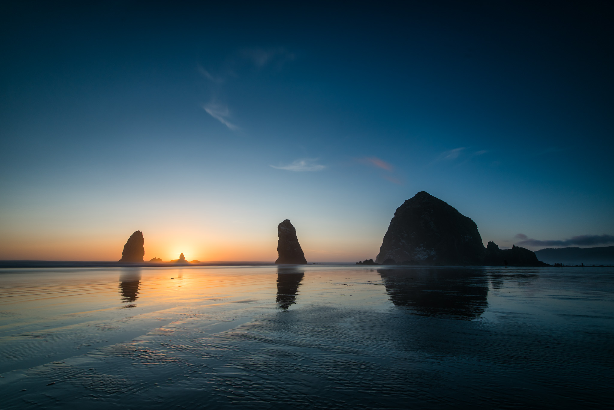 One of my shots of sunset as the sun disappears behind the smaller rock at Cannon Beach.