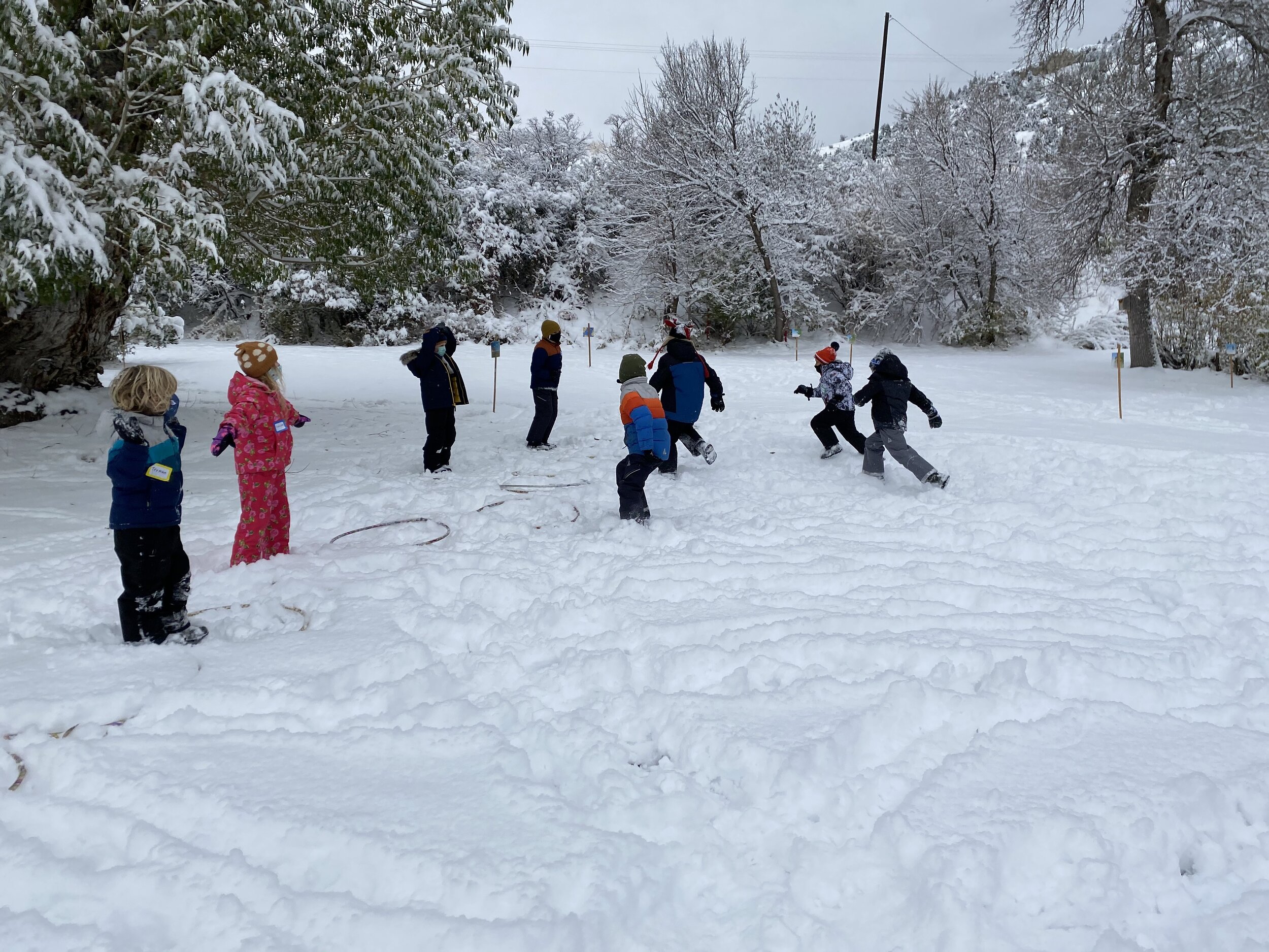 Kids run in snow on the MOSS campus.