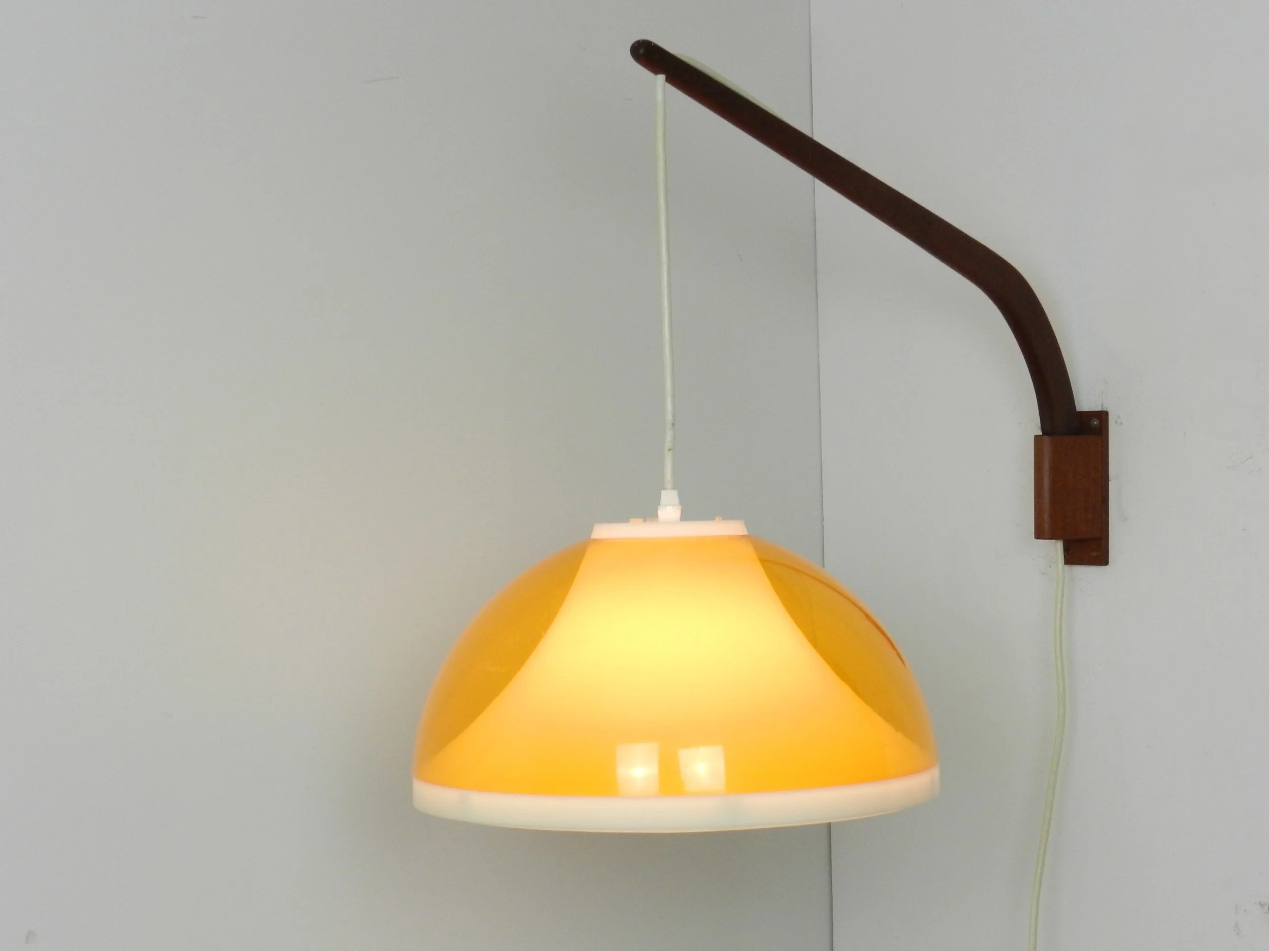 Mid century wall lamp with plastic shade and teak pivoting bracket. Scandinavia, 1960s.