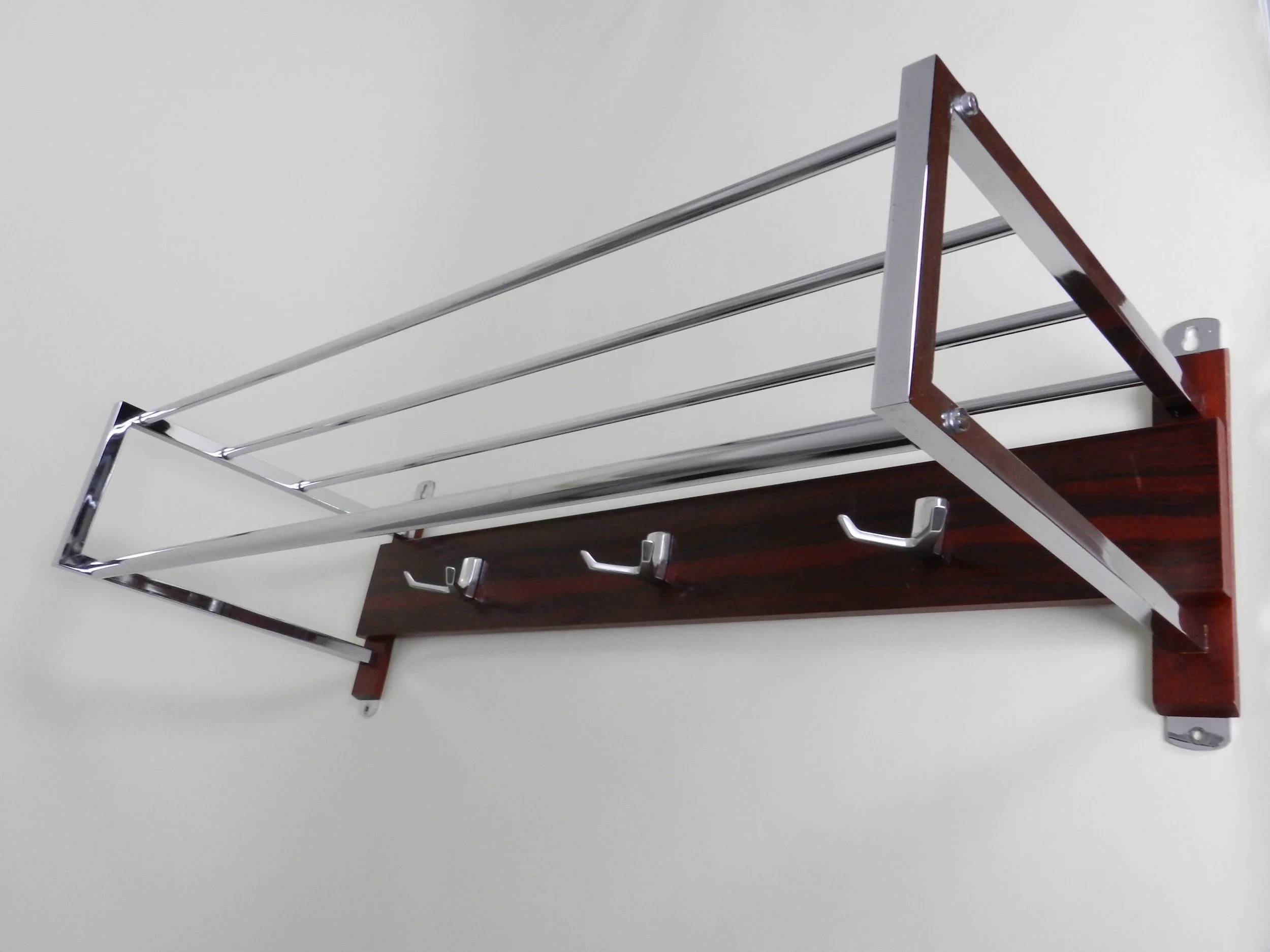 Modernist wall mounted coat rack in chrome, rosewood and cast aluminum.  Netherlands, 1960s.