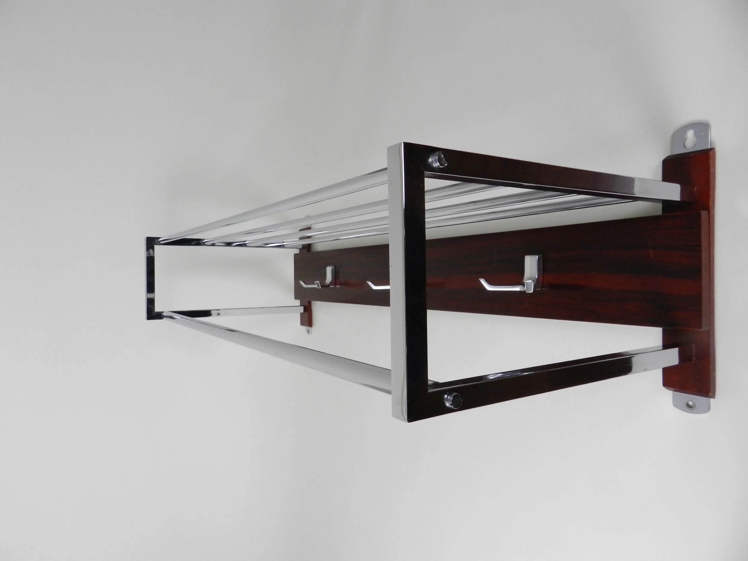 Modernist wall mounted coat rack in chrome, rosewood and cast aluminum.  Netherlands, 1960s.
