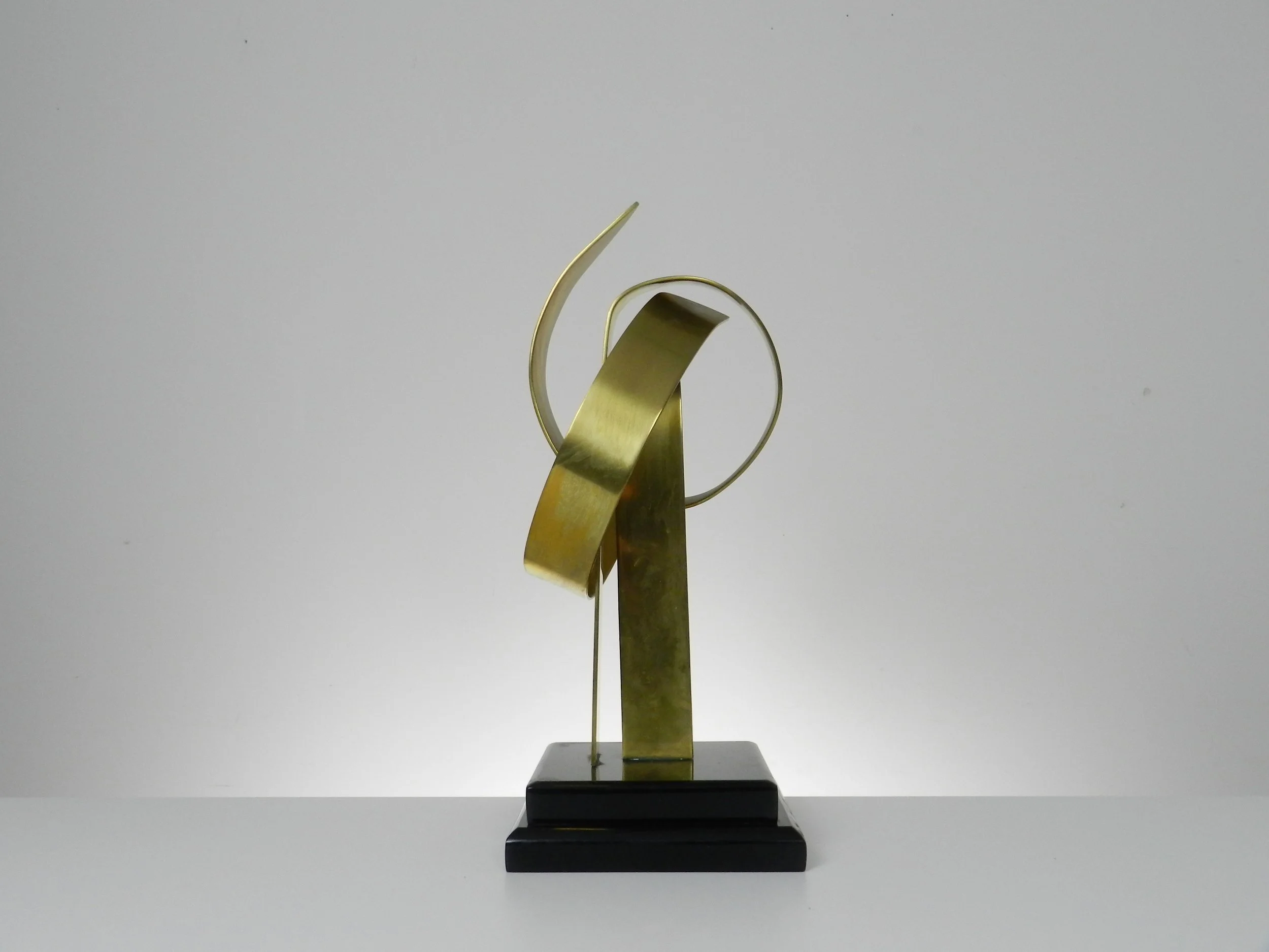 Abstract sculpture in lacquered brass and black acrylic base by Hivo G. Van Teal. Signed and numbered 1/12.  American, 1970s.