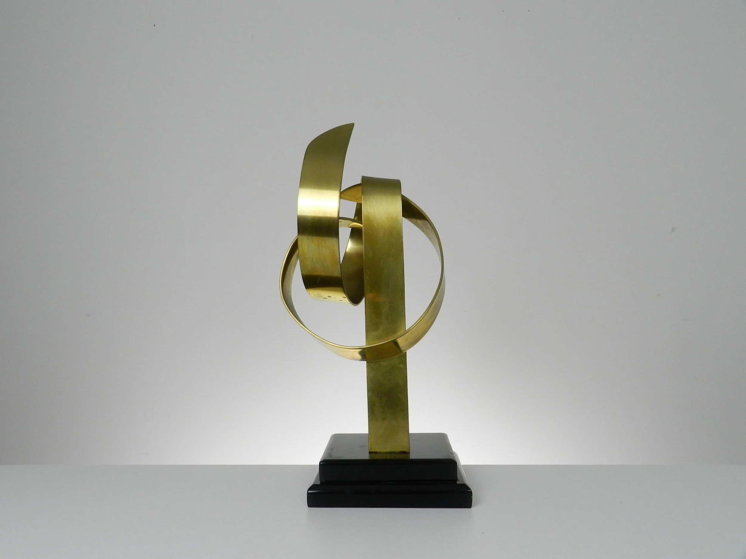 Abstract sculpture in lacquered brass and black acrylic base by Hivo G. Van Teal. Signed and numbered 1/12.  American, 1970s.