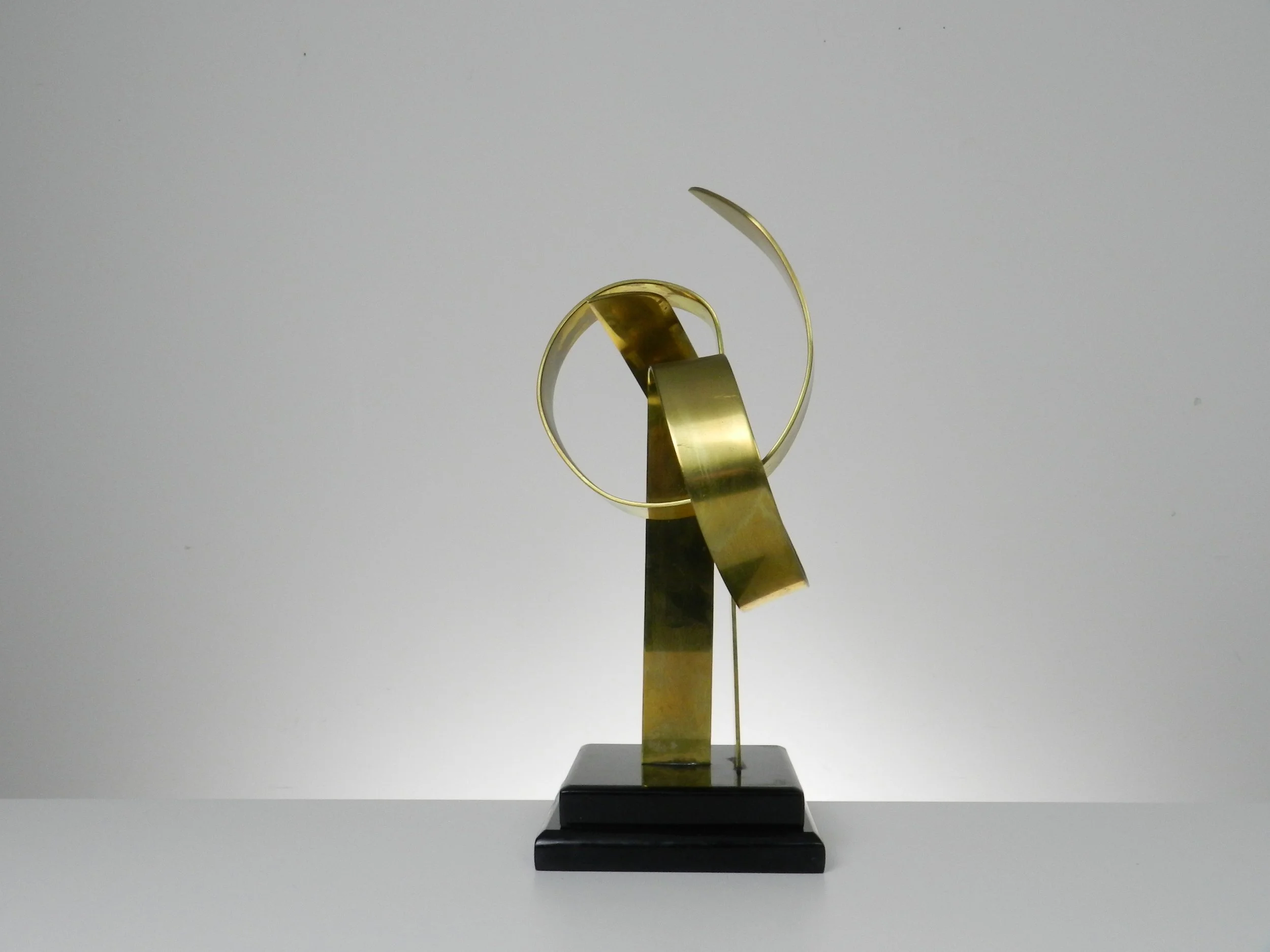 Abstract sculpture in lacquered brass and black acrylic base by Hivo G. Van Teal. Signed and numbered 1/12.  American, 1970s.