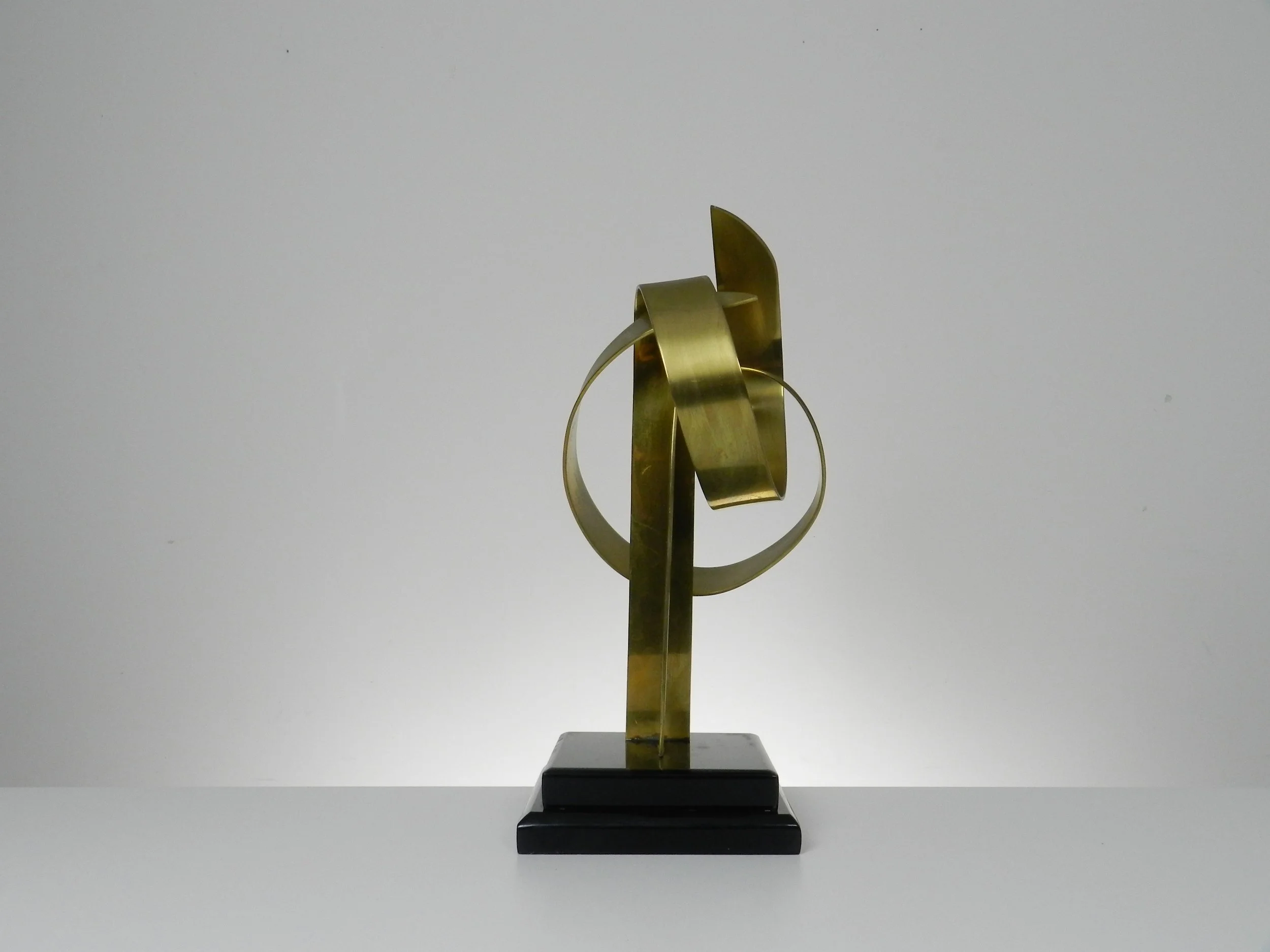 Abstract sculpture in lacquered brass and black acrylic base by Hivo G. Van Teal. Signed and numbered 1/12.  American, 1970s.