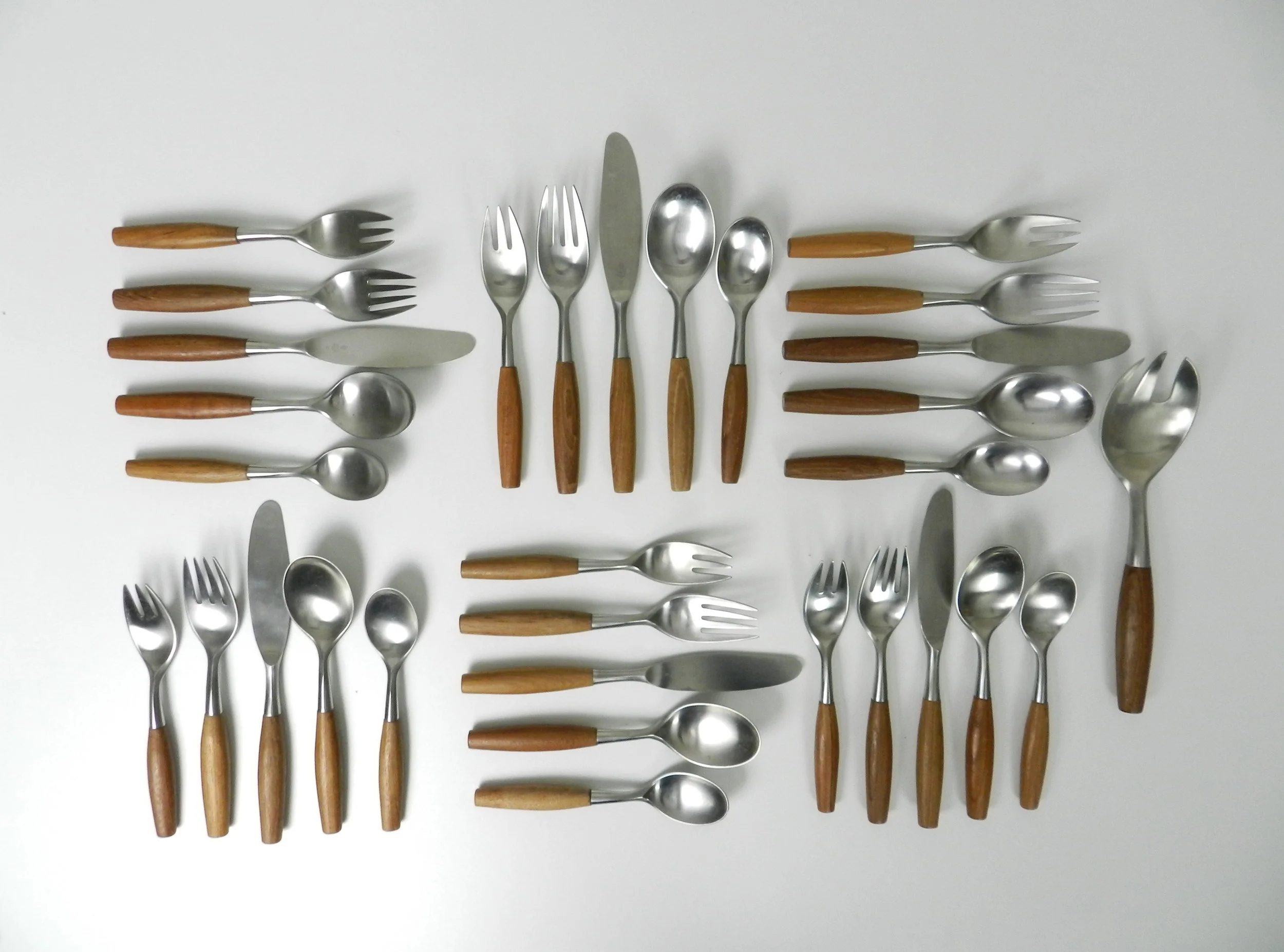 Set of Fjord flatware designed by Jens Quistgaard for Dansk. Stainless steel with teak handles. 6 complete place setttings of 5 plus one serving utensil, 31 pieces total.  Germany, 1960s.