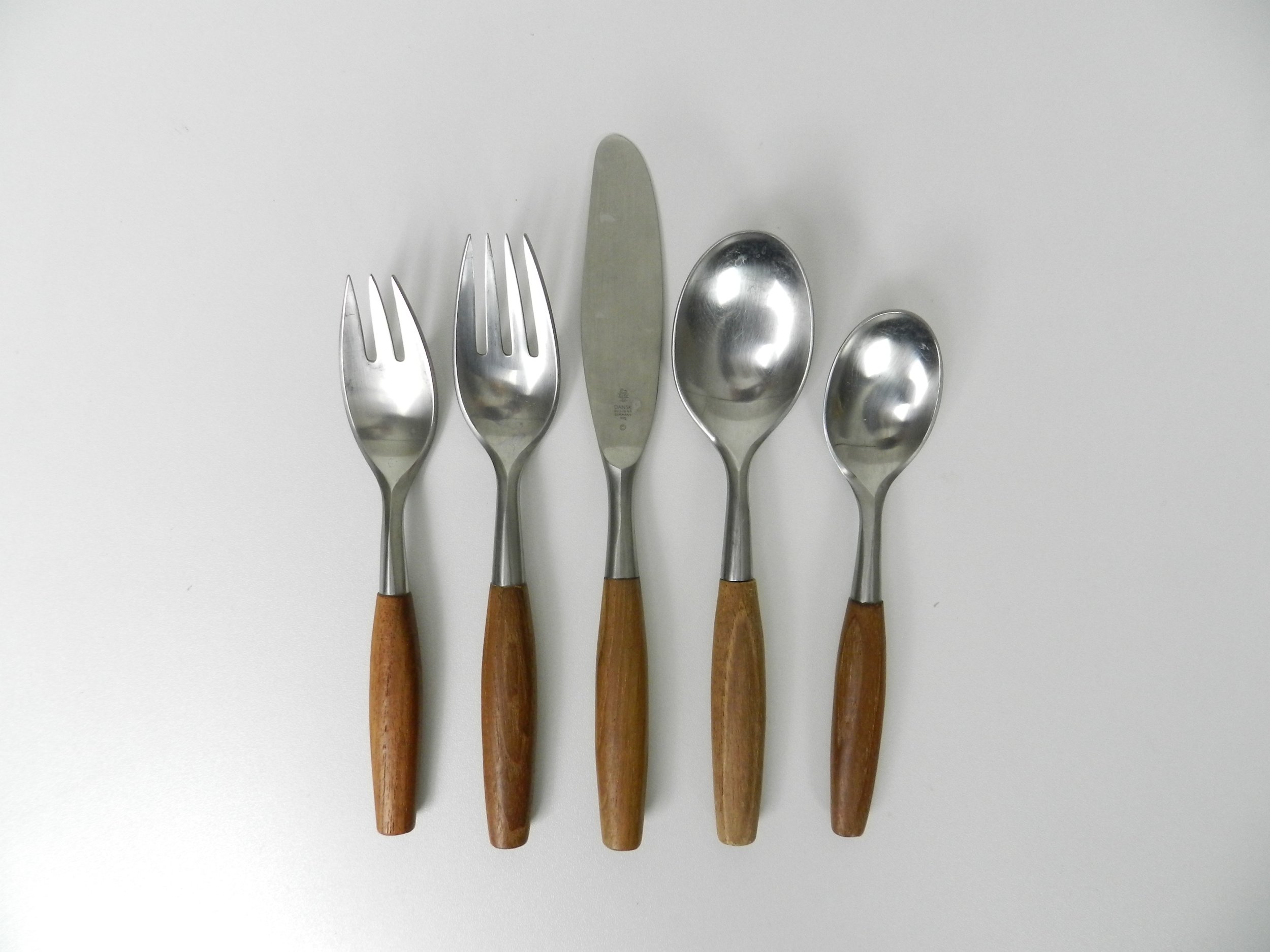 Set of Fjord flatware designed by Jens Quistgaard for Dansk. Stainless steel with teak handles. 6 complete place setttings of 5 plus one serving utensil, 31 pieces total.  Germany, 1960s.