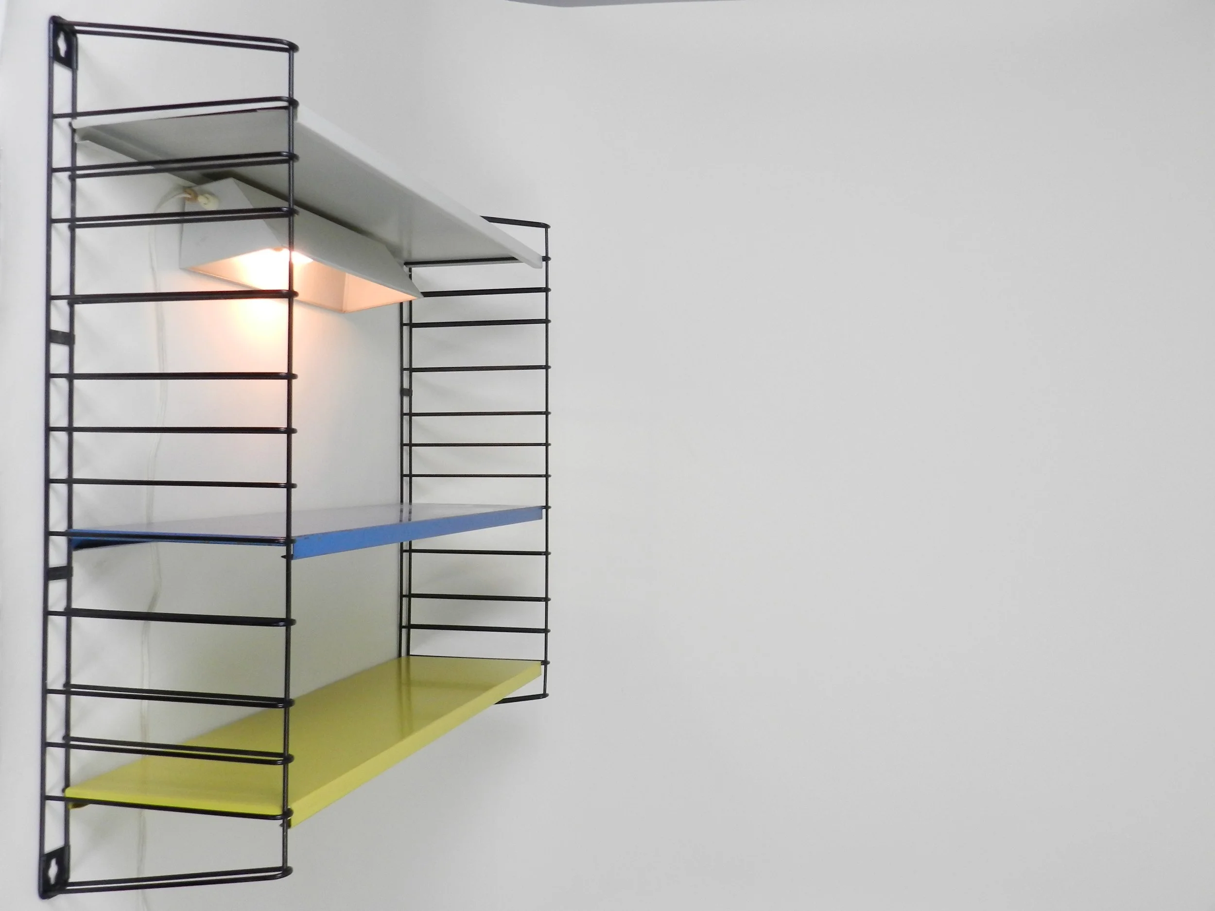 Mid century metal wall mount shelving unit with lamp by Tomado.  Netherlands, 1960s.