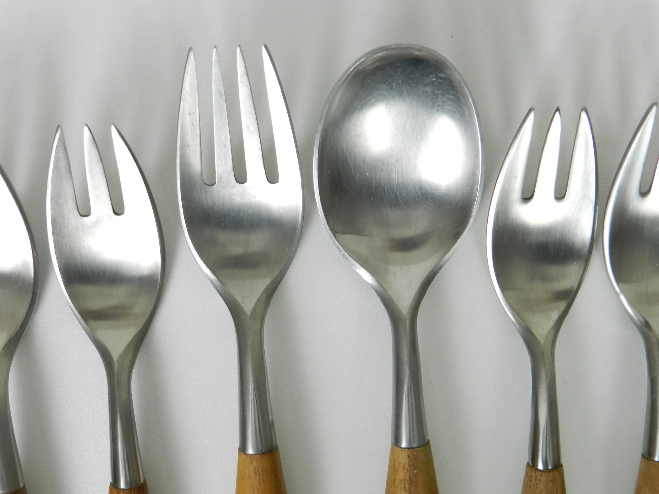 Stainless steel and teak Fjord flatware deigned by Jens Quistgaard for Dansk. Set includes 7 salad/desert forks, 1 dinner fork amd 1 soup spoon.  Germany, 1960s.