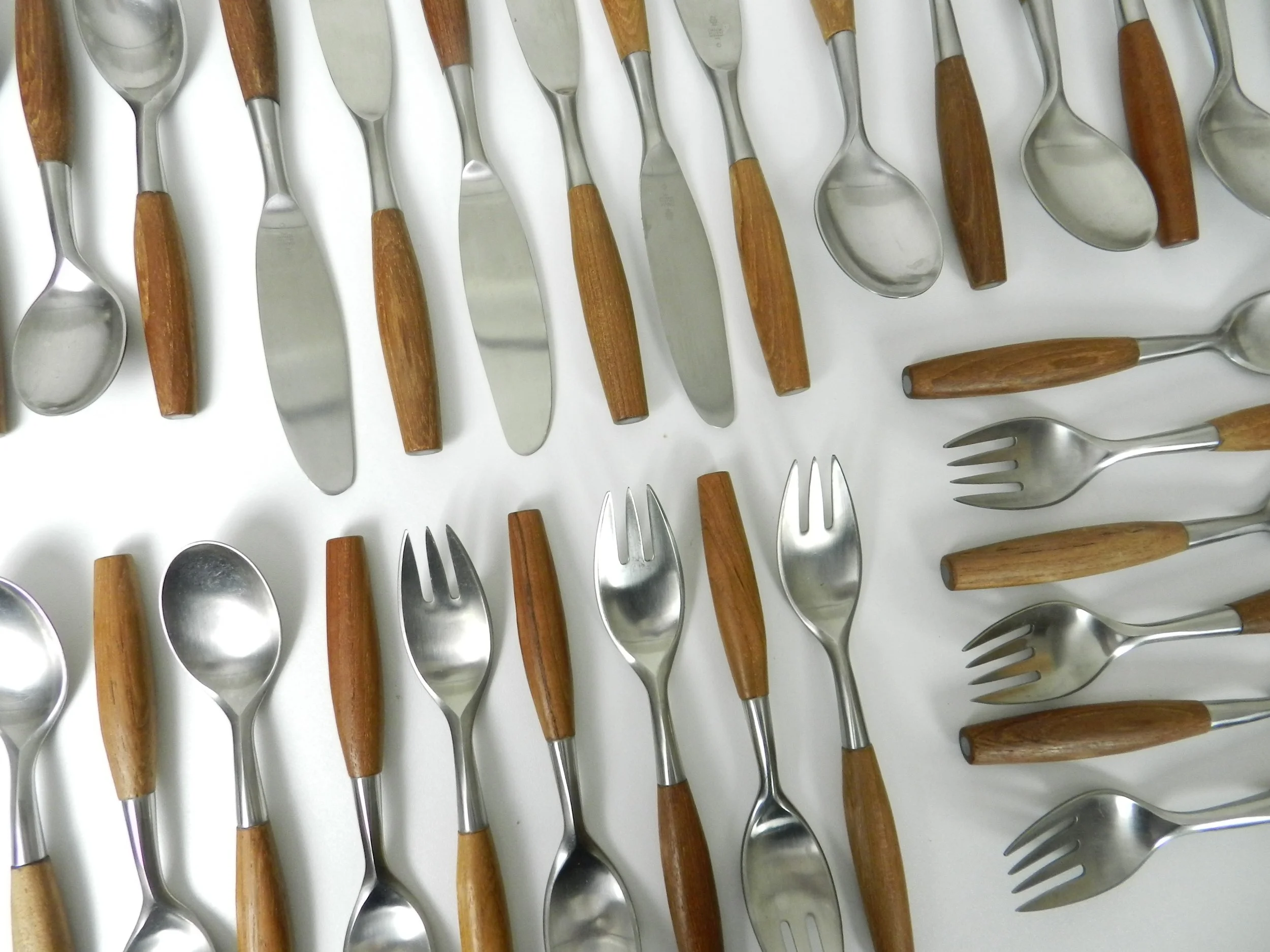 Set of Fjord flatware designed by Jens Quistgaard for Dansk. Stainless steel with teak handles. 6 complete place setttings of 5 plus one serving utensil, 31 pieces total.  Germany, 1960s.