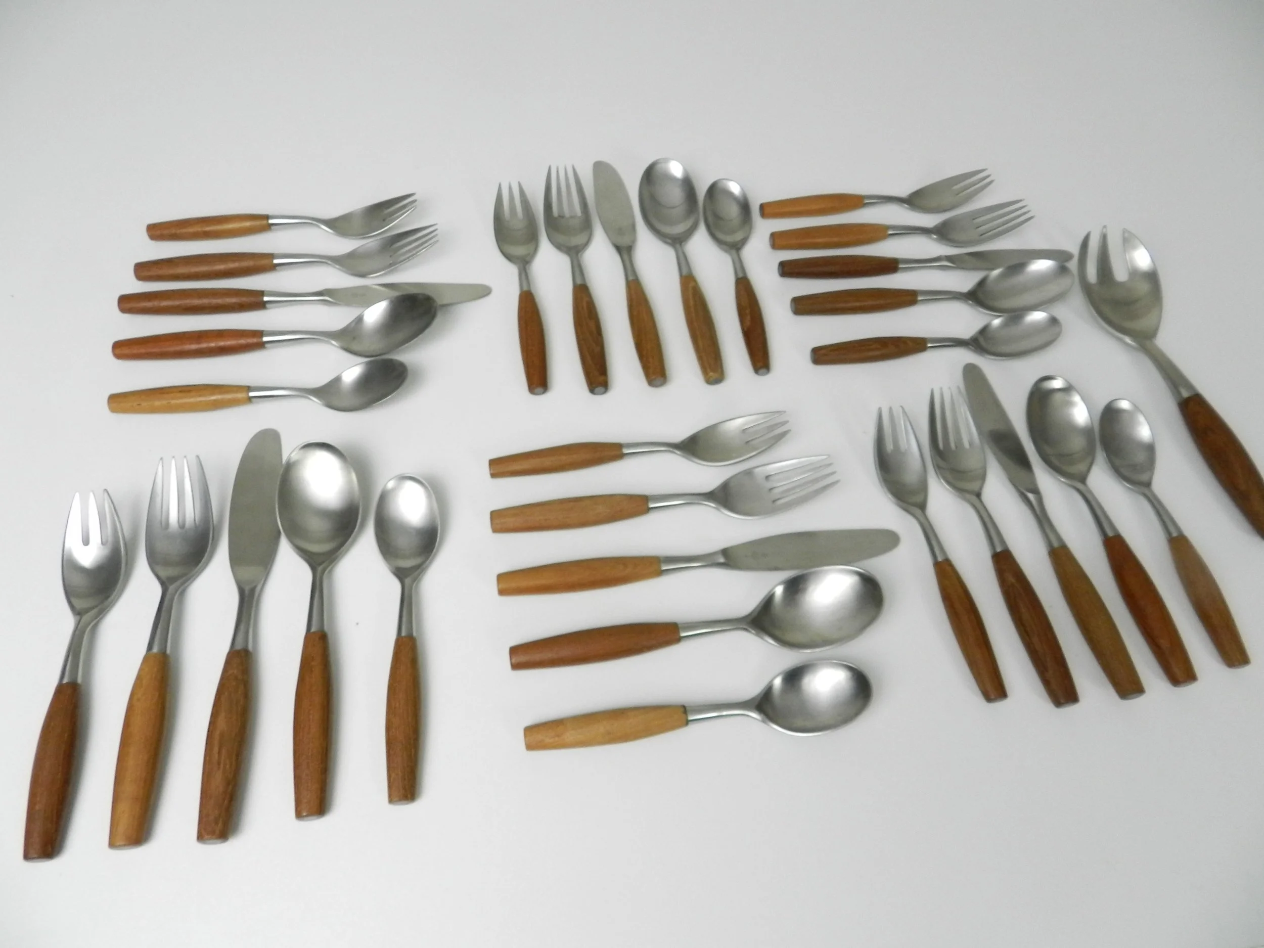 Set of Fjord flatware designed by Jens Quistgaard for Dansk. Stainless steel with teak handles. 6 complete place setttings of 5 plus one serving utensil, 31 pieces total.  Germany, 1960s.