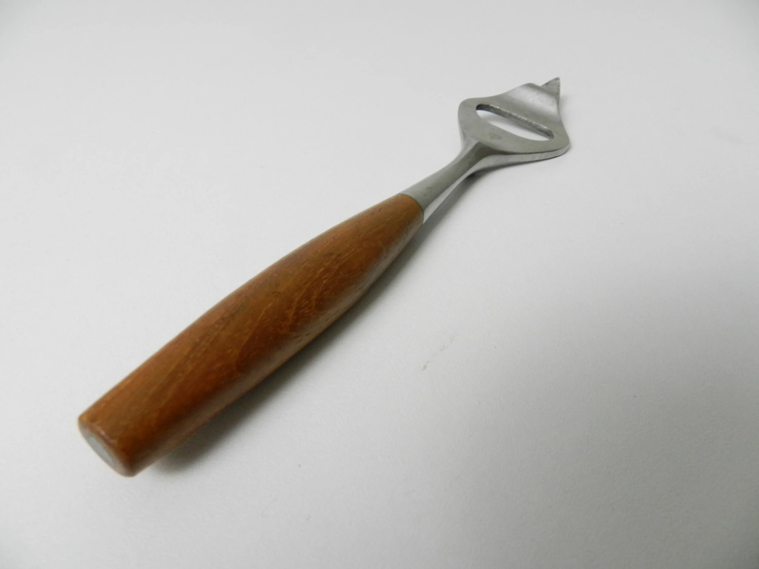 Fjord can/bottle opener designed by Jens Quistgaard for Dansk. Stainless steel with teak handle.  Germany, 1960s.