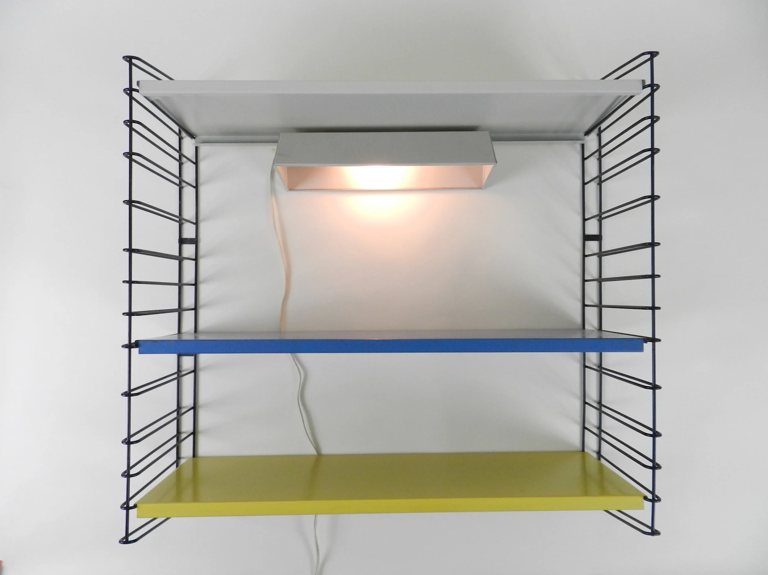 Mid century metal wall mount shelving unit with lamp  by Tomado.  Netherlands, 1960s.