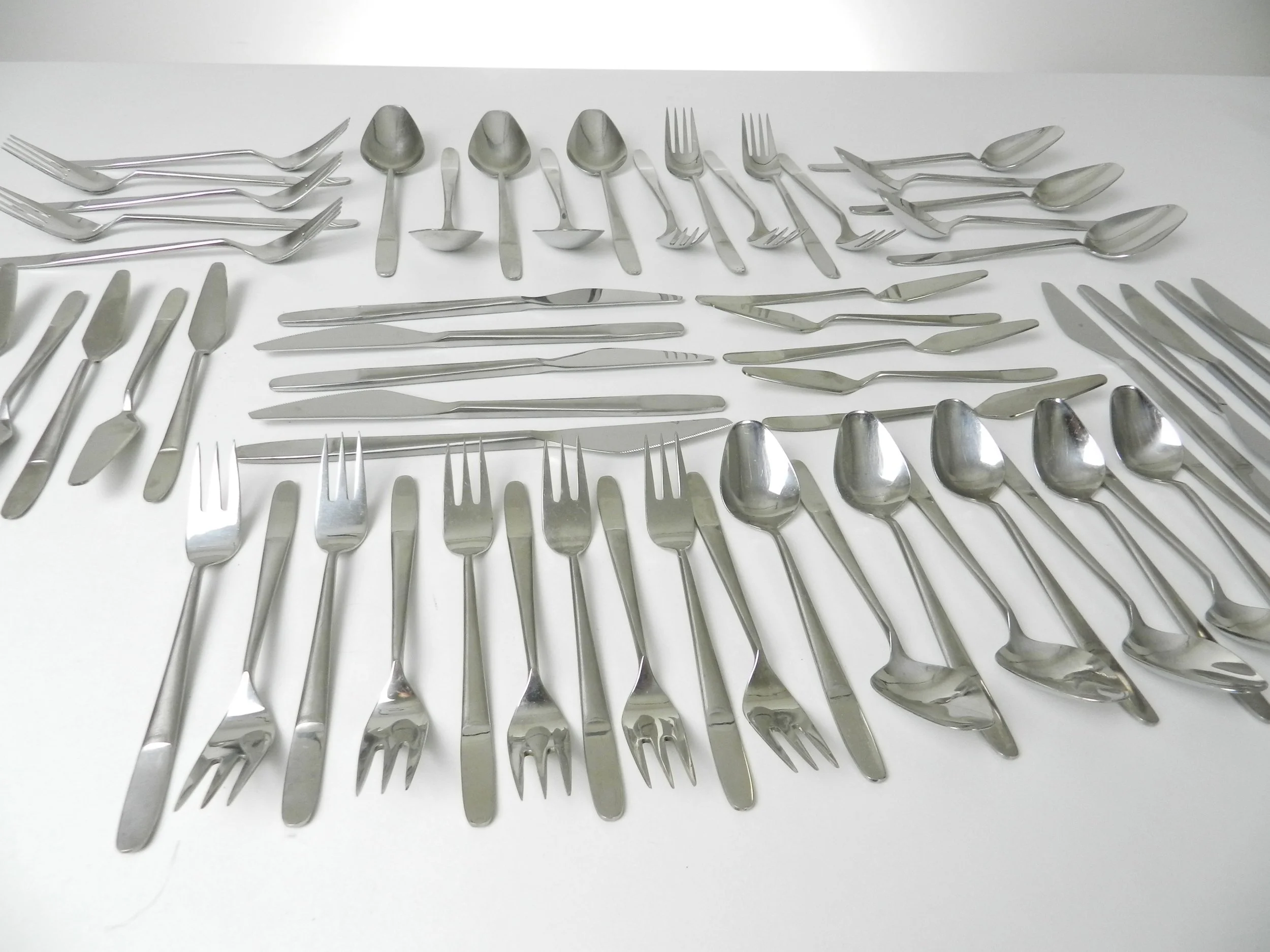 Modernist stainless steel flatware set (model 2070) designed by Helmut Alder for Amboss. Six piece place settings for 10 plus 10 extra pieces, total of 70.  Austria, 1960s.
