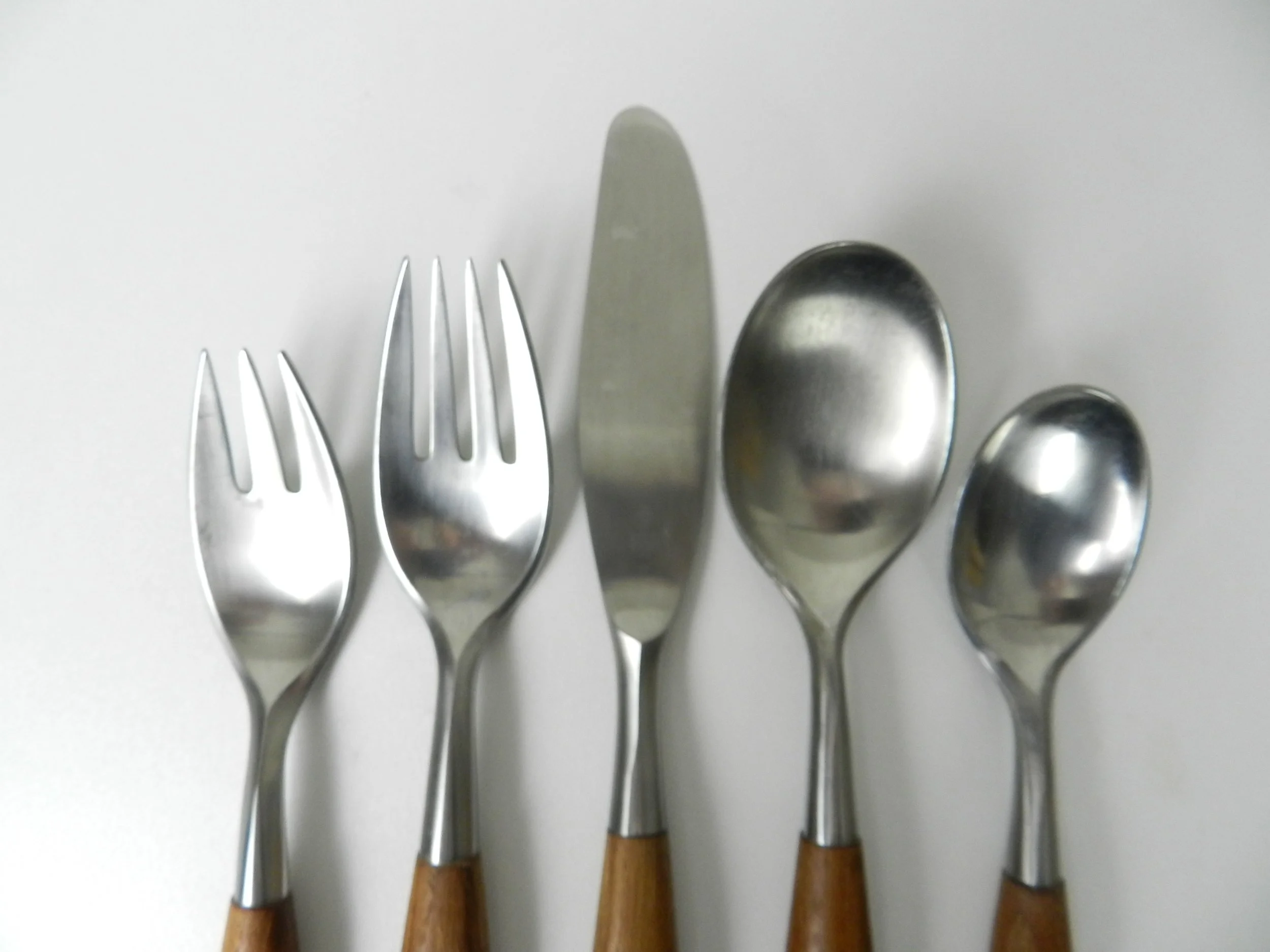 Set of Fjord flatware designed by Jens Quistgaard for Dansk. Stainless steel with teak handles. 6 complete place setttings of 5 plus one serving utensil, 31 pieces total.  Germany, 1960s.