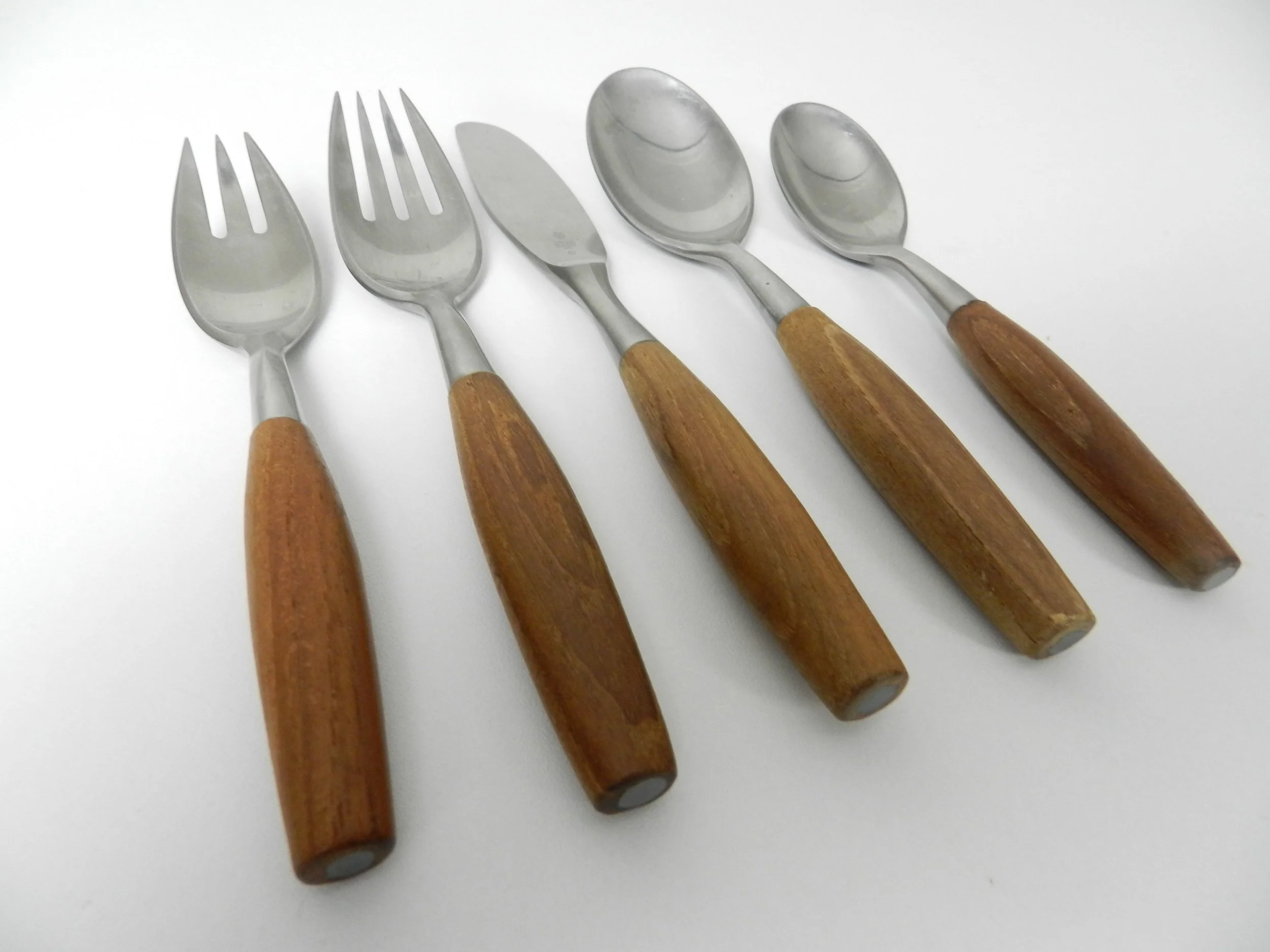 Set of Fjord flatware designed by Jens Quistgaard for Dansk. Stainless steel with teak handles. 6 complete place setttings of 5 plus one serving utensil, 31 pieces total.  Germany, 1960s.