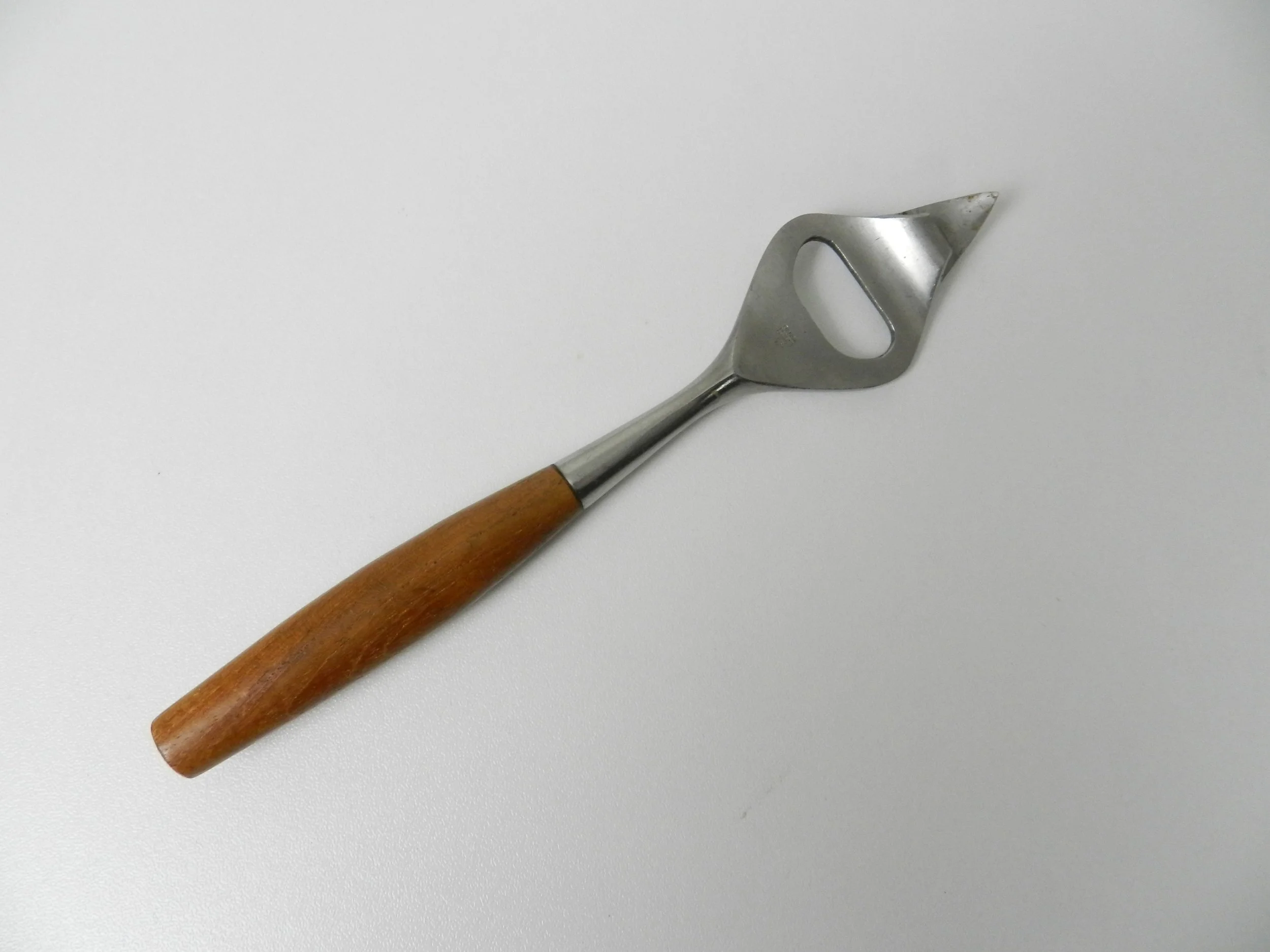 Fjord can/bottle opener designed by Jens Quistgaard for Dansk. Stainless steel with teak handle.  Germany, 1960s.