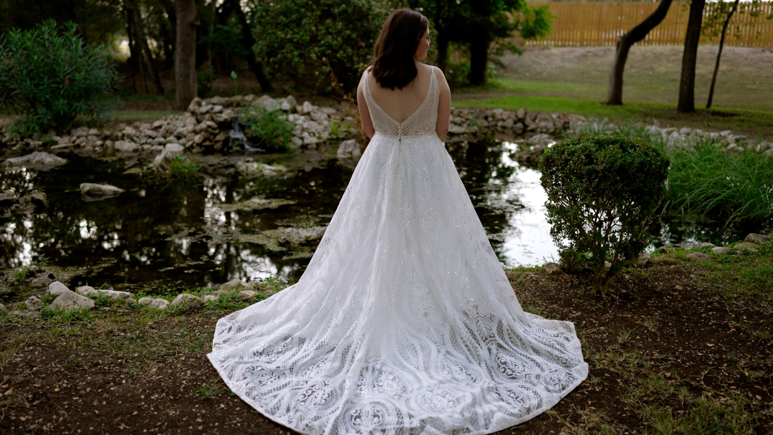 back of bride dress posed next to pond outside