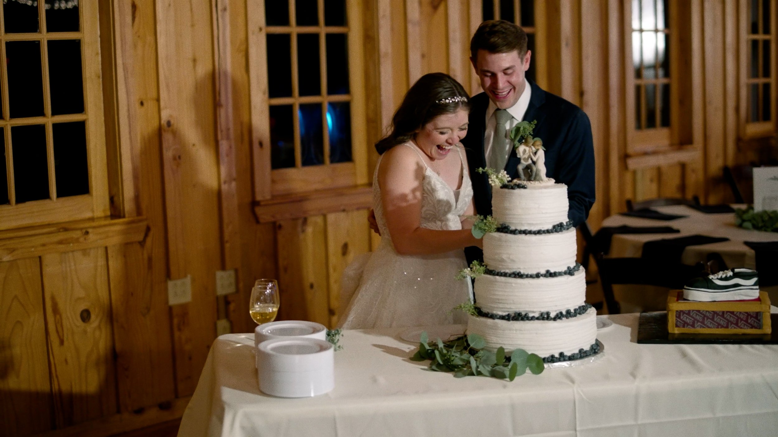 bride and groom cut wedding cake laughing