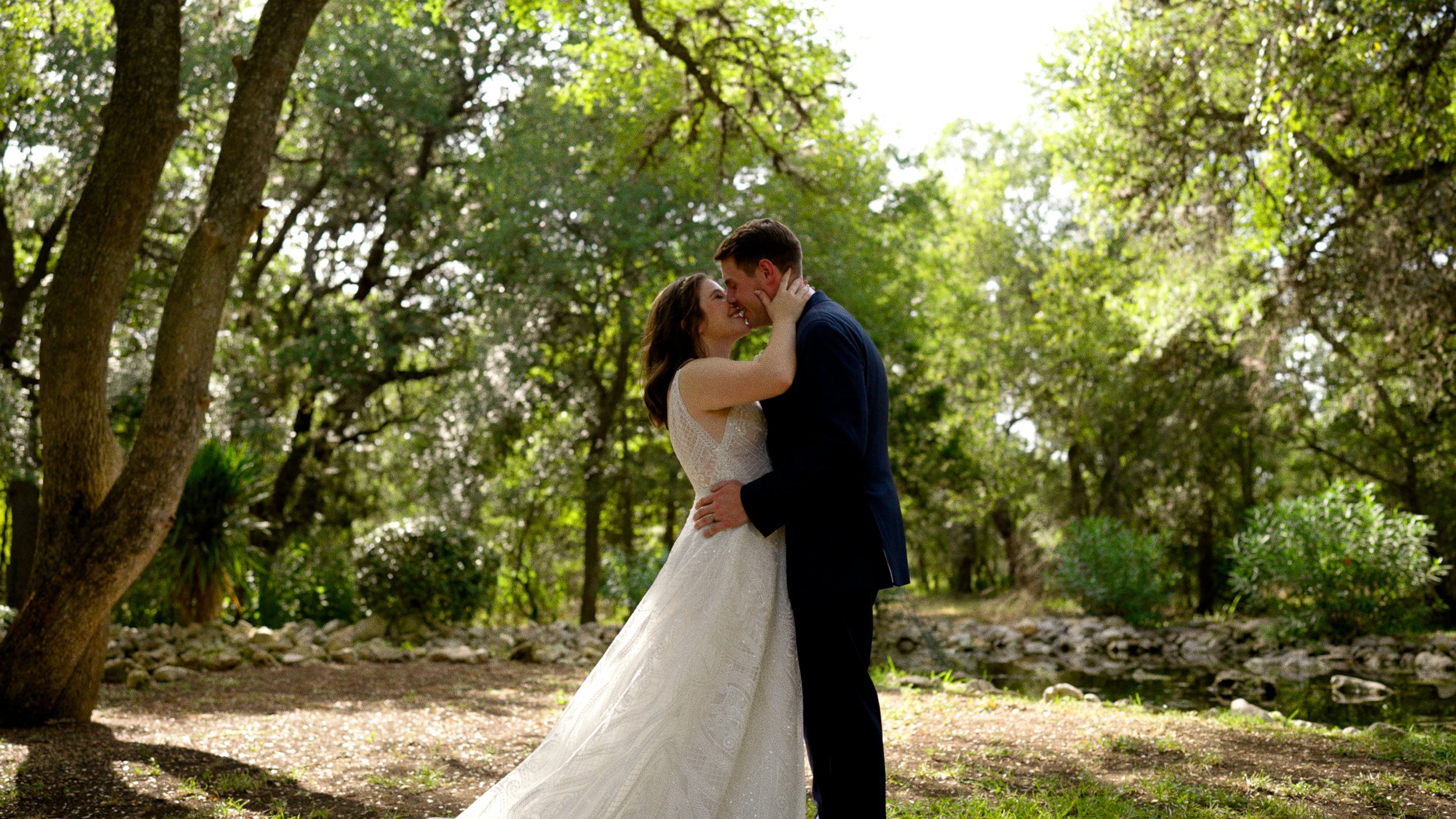 bride and groom almost kiss wide outside next to pond