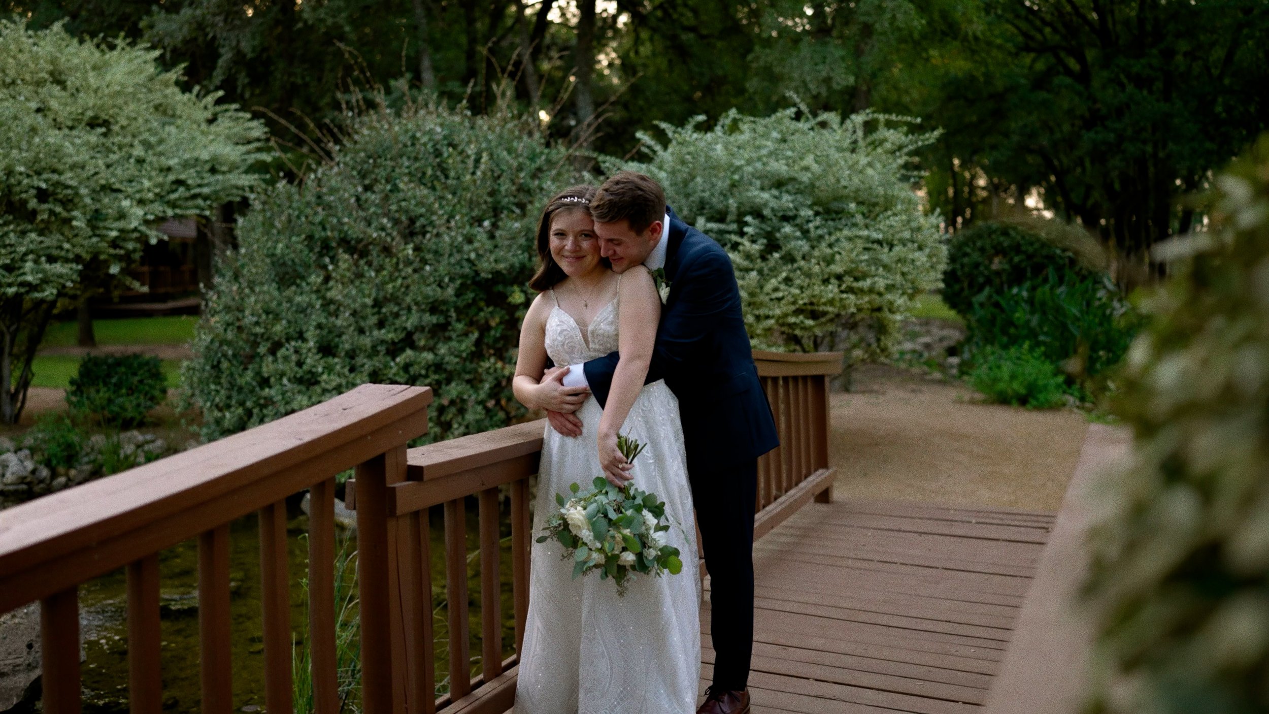 bride and groom embrace on bridge soft smiles