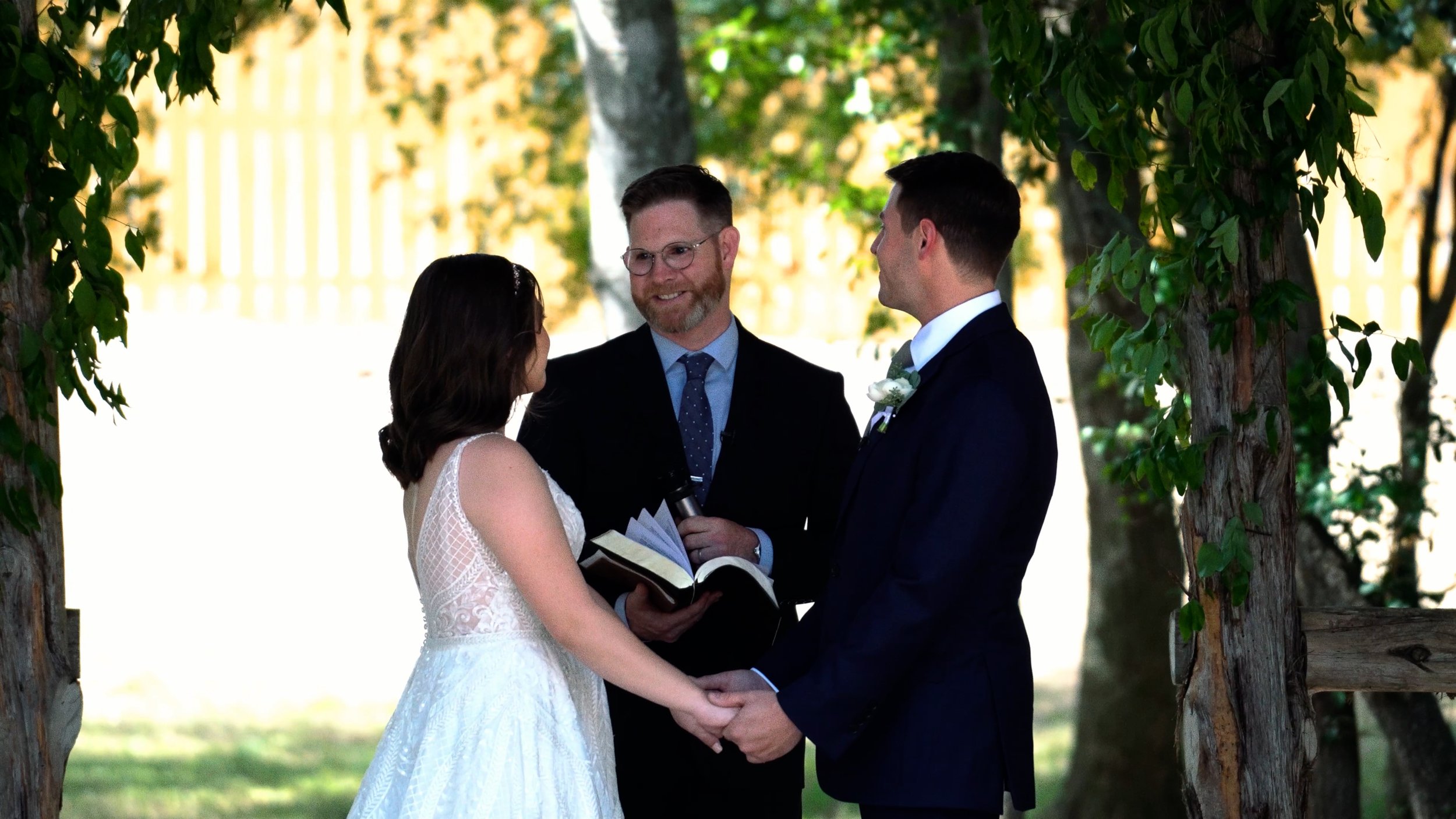 bride and groom hold hands at altar during wedding ceremony