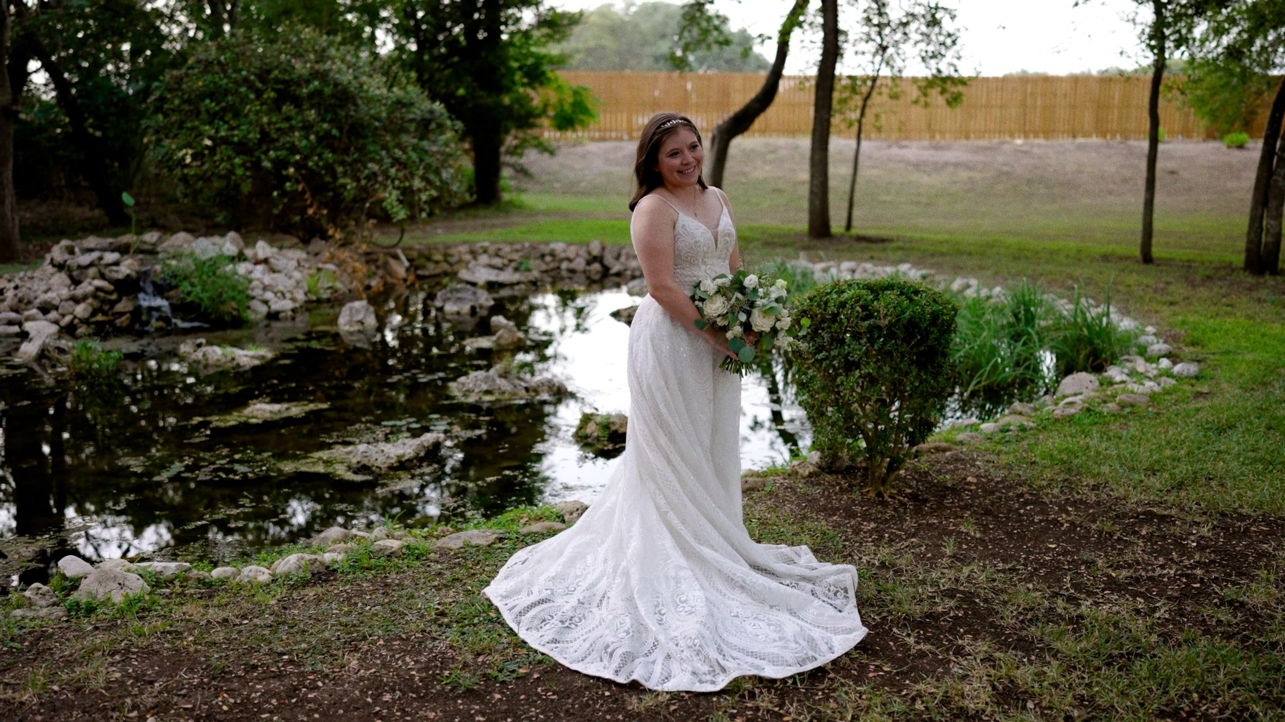 bride full length dress pose outside next to pond with bridal bouquet