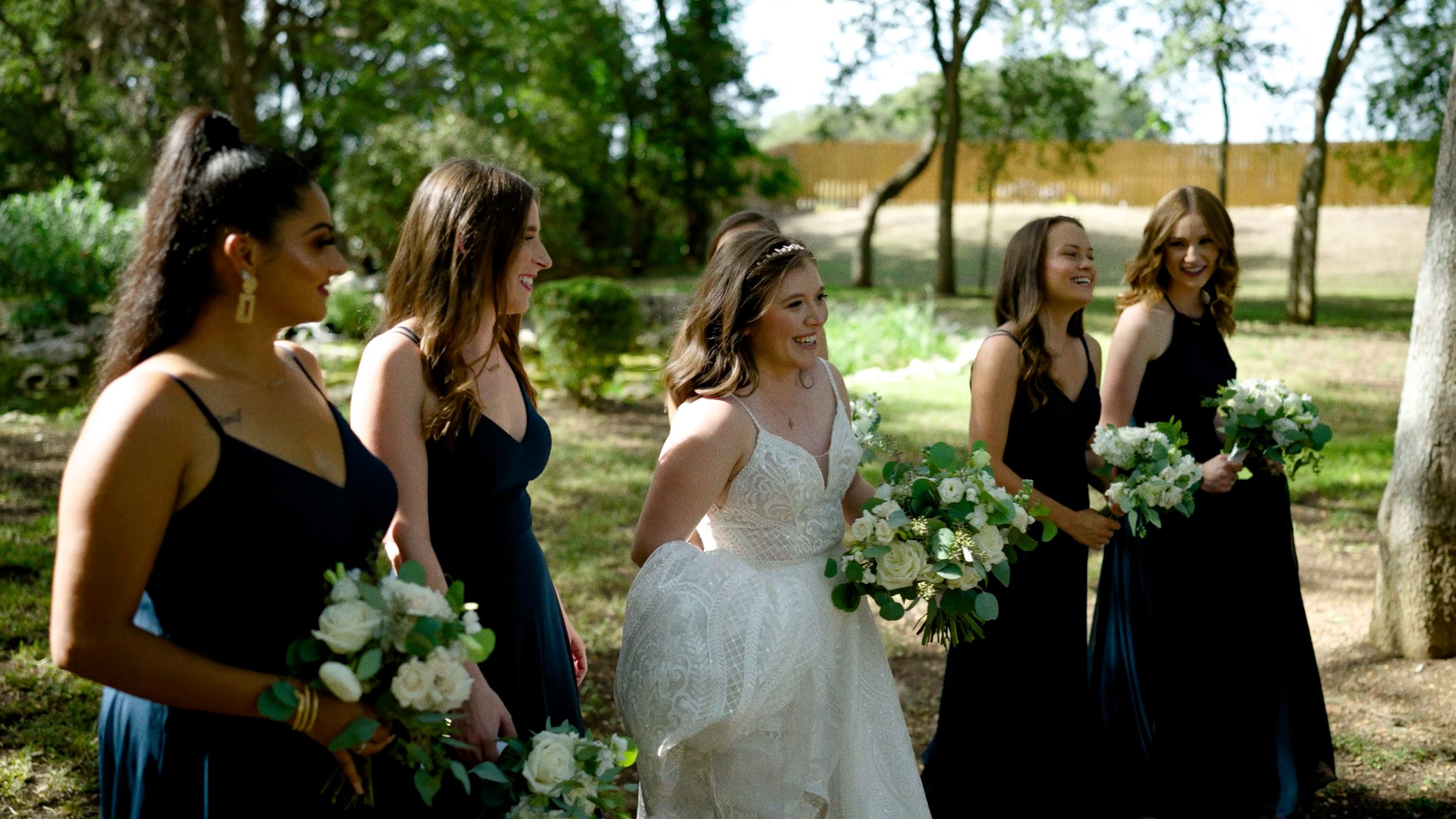 bride walks with bridesmaids outside with bouquets