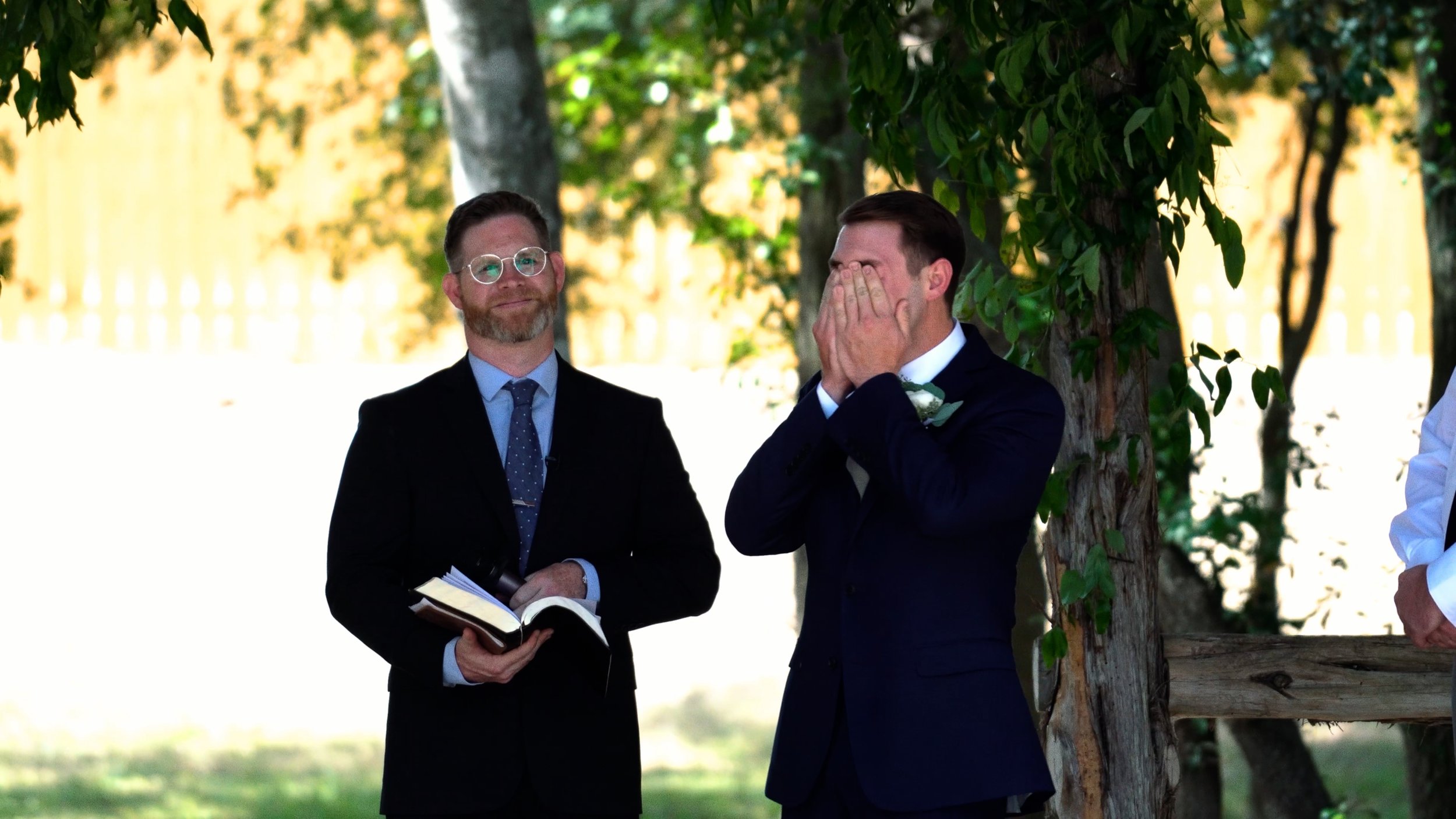 emotional groom crying seeing bride walk down aisle at wedding ceremony covers face