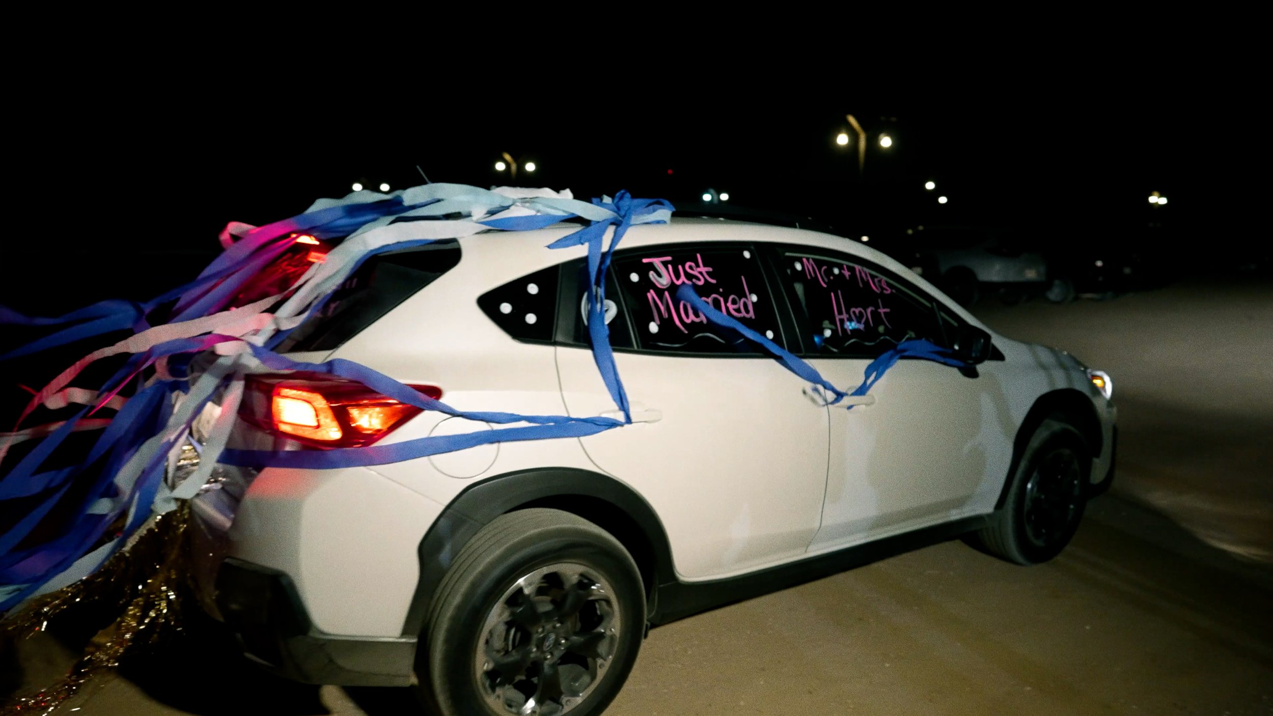 getaway car decorated with streamers and car paint drives away from reception