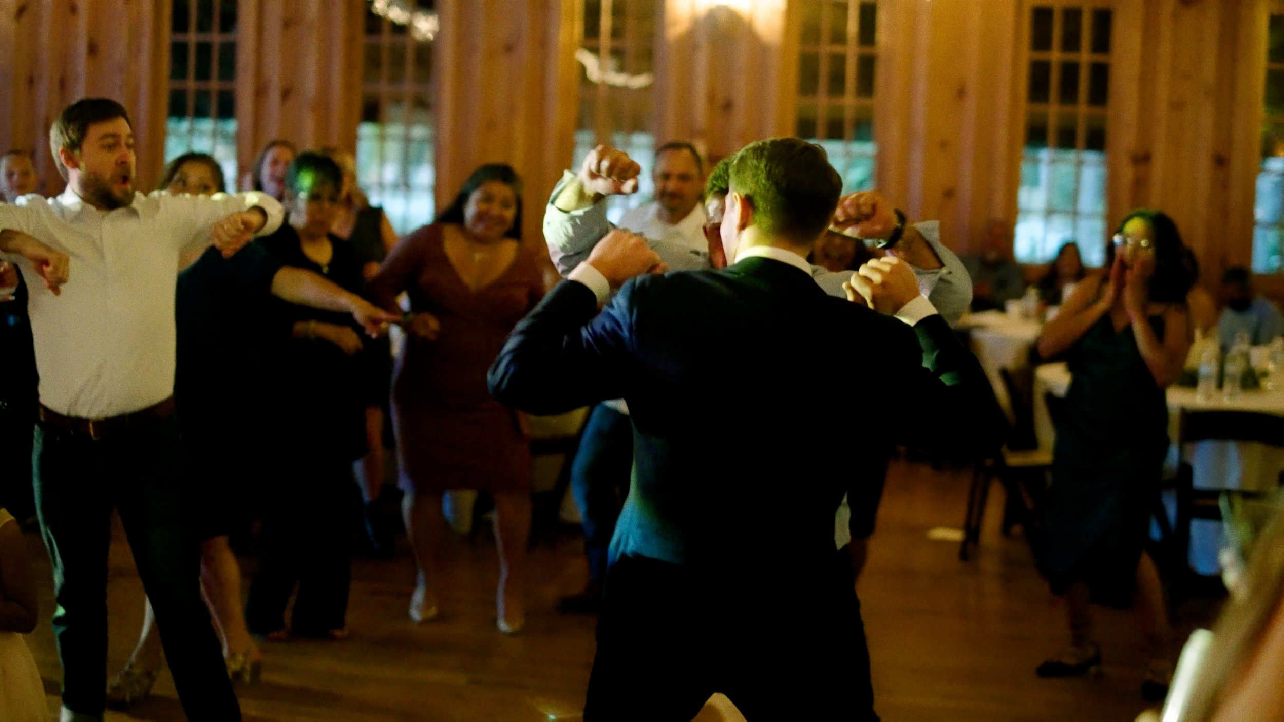 groom dances with guest on dance floor at wedding reception
